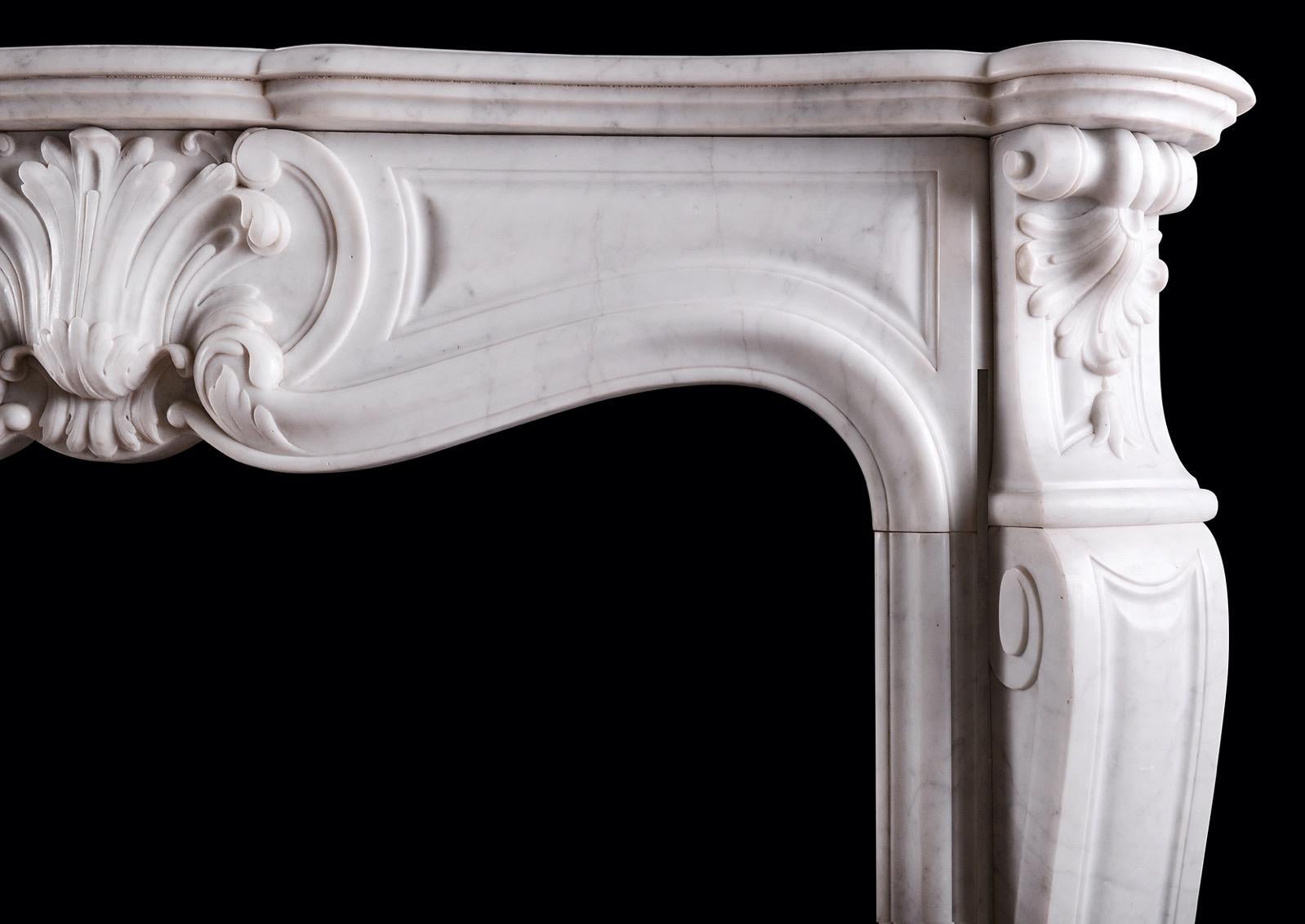 A 19th century French Carrara marble fireplace in the Louis XV style. The shaped jambs surmounted by shells and scrollwork. The shaped frieze with carved cartouche to centre flanked by panels. Shaped, moulded shelf above. Circa 1860. 

Shelf Width:	