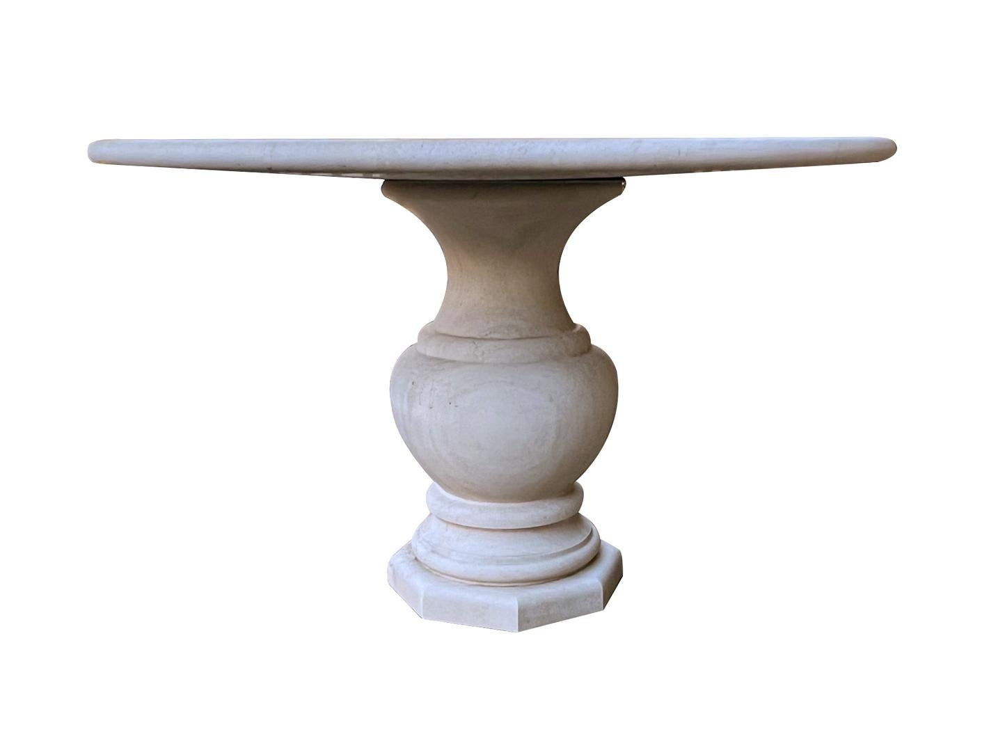 Cette table de style classique, fabriquée à la main en France, présente un épais plateau circulaire à bord arrondi ; elle repose sur une base robuste et galbée de forme balustre ; la surface présente une usure et une patine uniformes dans l'ensemble.