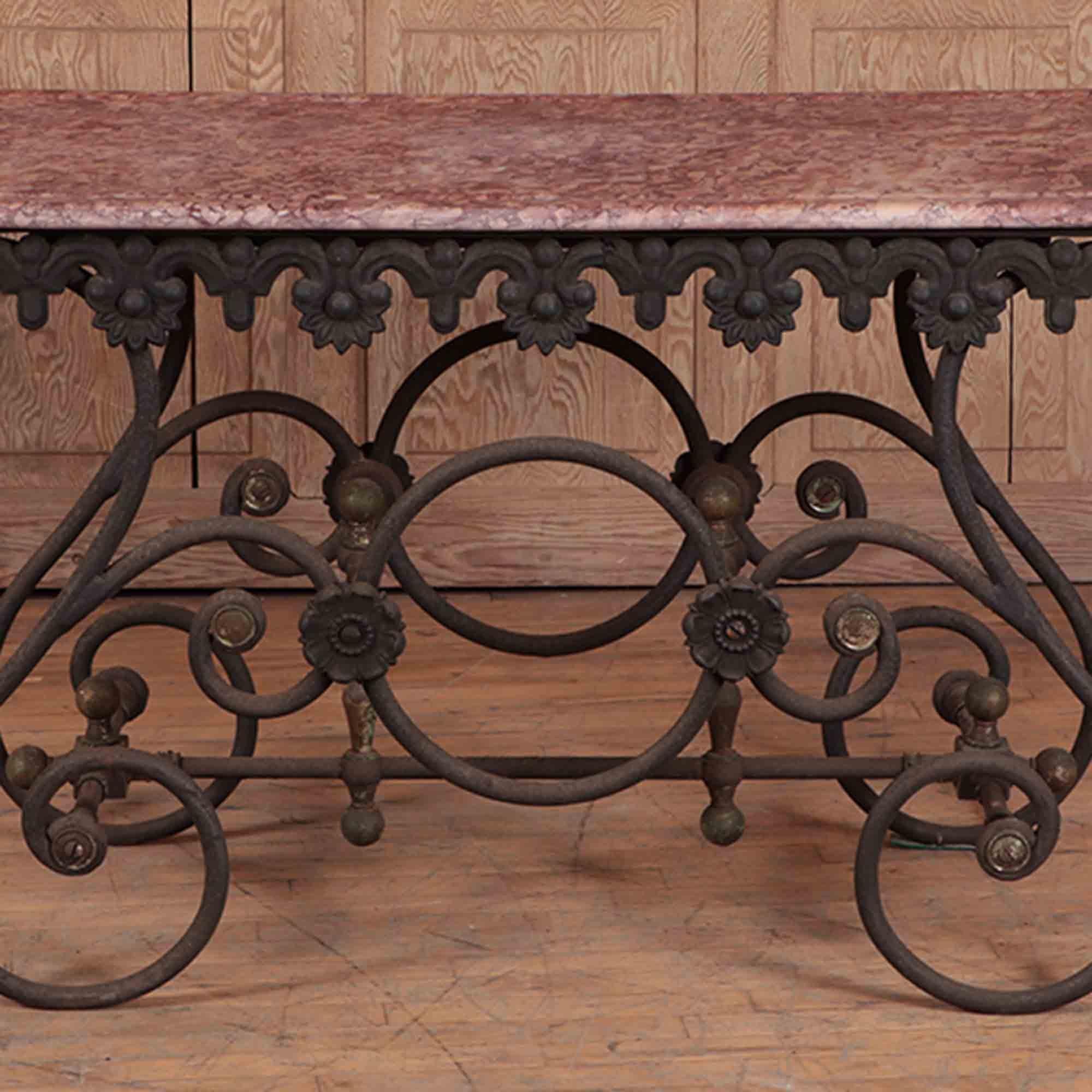 A French cast iron and marble bakers table with decorative floral details around the perimeter and finials in each corner. Ball finials decorate the joints on the stretchers underneath. Early 20th century.