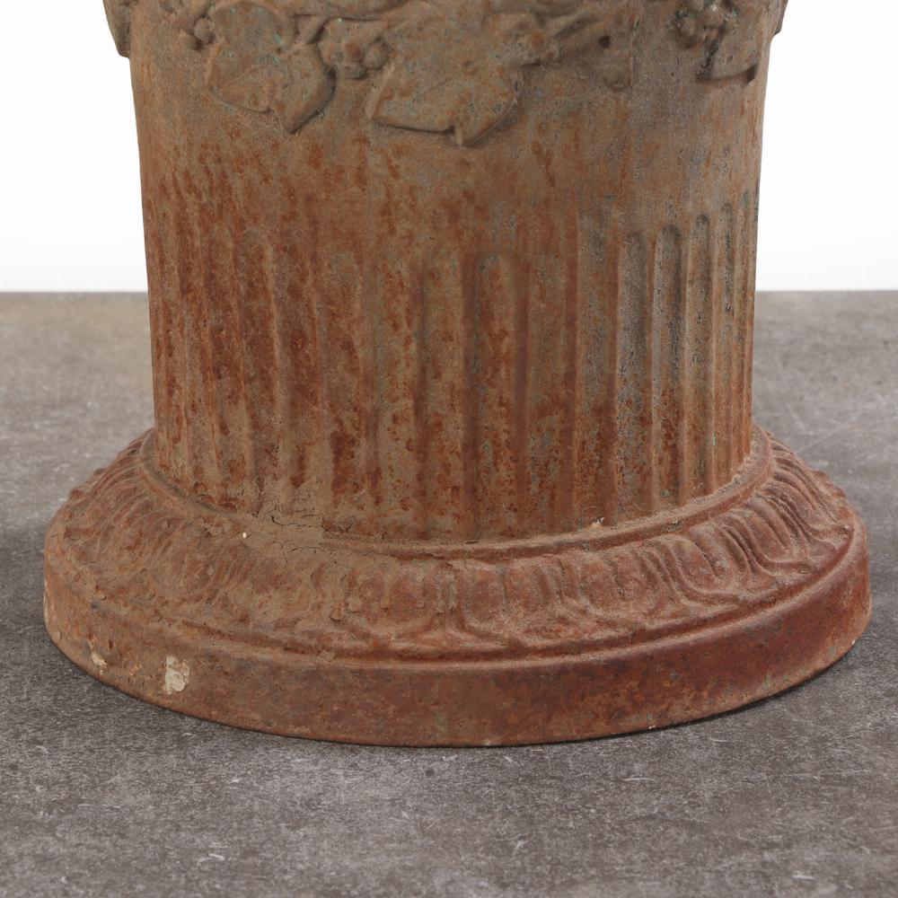 Elegant and timeless, this authentic French cast iron urn features classic Louis XVI styling with ornate grape and leaf motif above finely fluted band. Beautifully aged with a natural weathered patina, this urn make a striking garden accents or