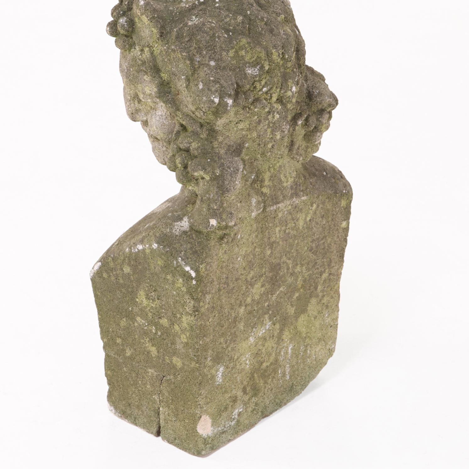 Affascinante busto di una figura sorridente adornata da grappoli d'uva intrecciati tra i capelli, che evocano la classica immagine bacchica. Realizzato in pietra fusa con una patina delicatamente invecchiata, questo pezzo porta un tocco di scultura