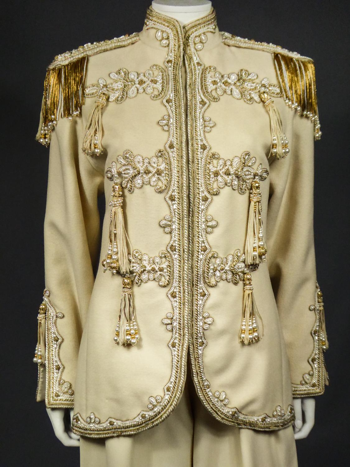 Circa 1990/1995
France

A military-inspired trouser suit in beige wool by Jean-Louis Scherrer under the direction of Stephane Rolland from the 1990s. Officer jacket with high collar and fringed epaulettes richly embroidered with pearly pearls and