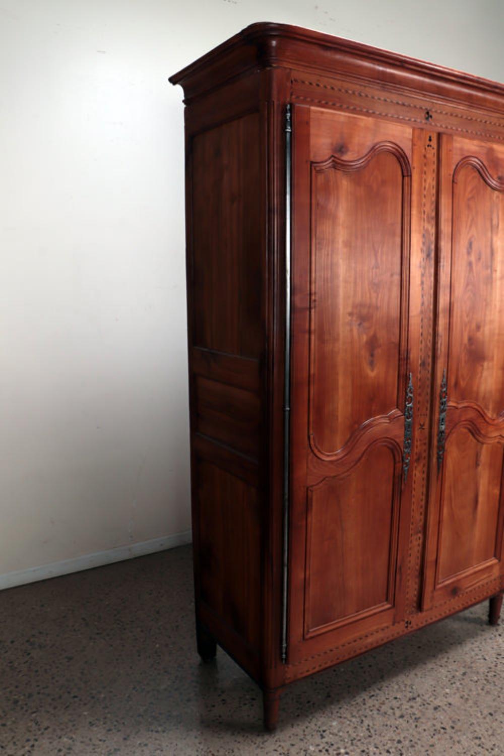 Armoire en cerisier français avec incrustation, vers 1800. La grande caisse à panneaux est dotée d'une corniche moulurée, d'incrustations de style 