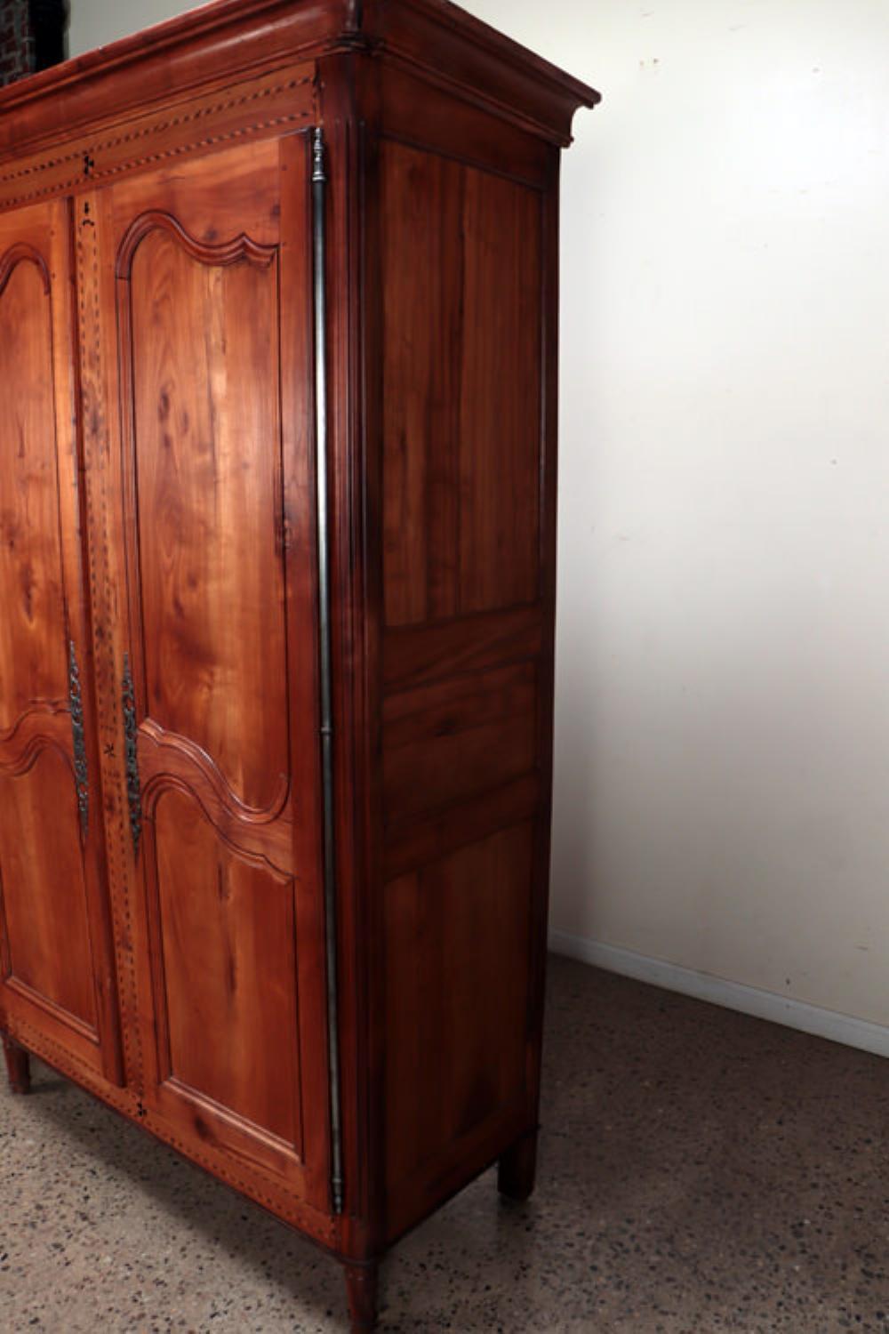 Français Une armoire française en cerisier avec incrustation de bandes, vers 1800. en vente