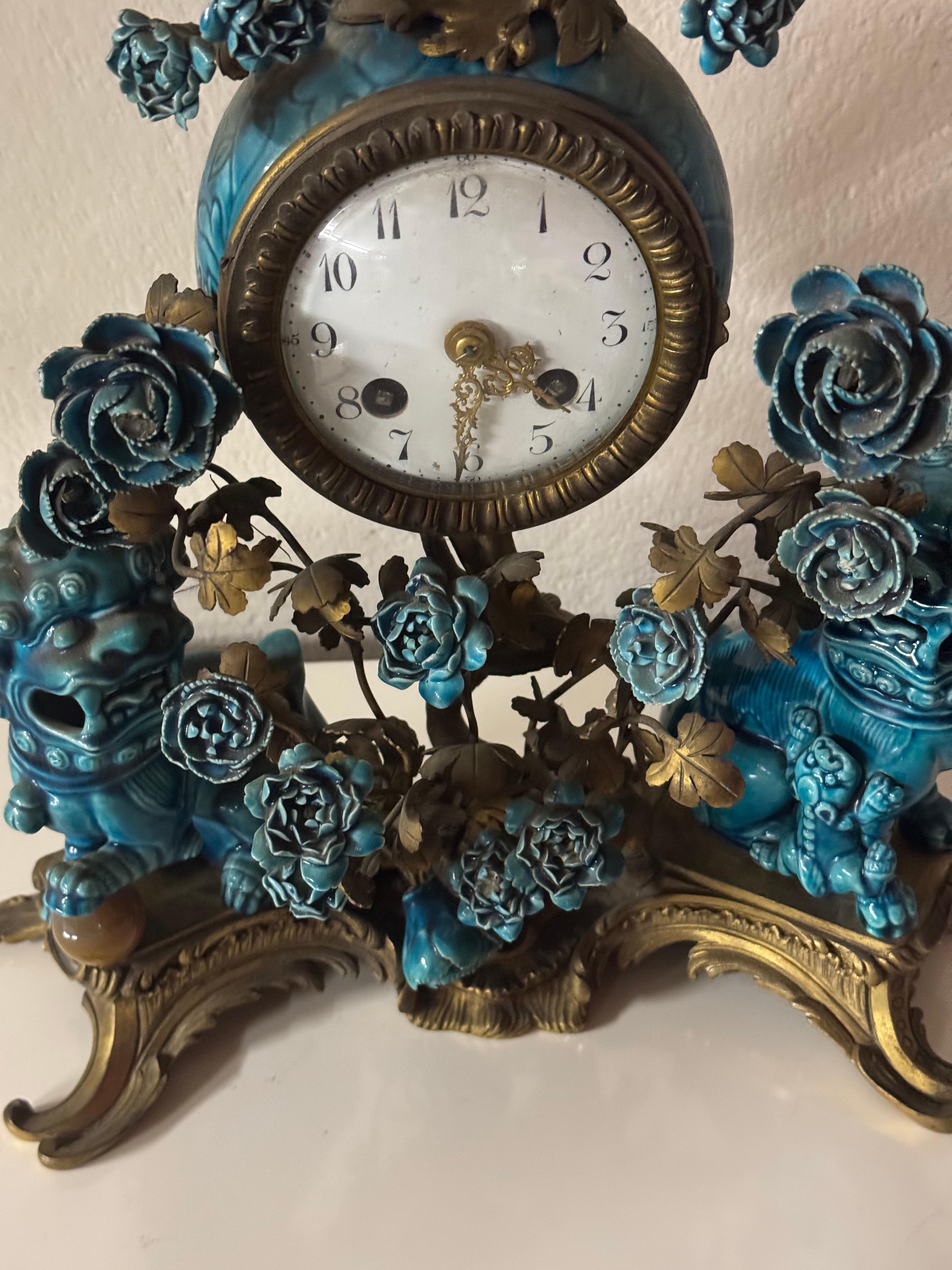 A french chinoiserie style three pieces gilt bronze and porcelain  .The magnificent clock have a base in bronze ,each side of the base is surmounted  by two turquoise glazed porcelain foo dogs and floral blossoms, on the top the clock is surmounted
