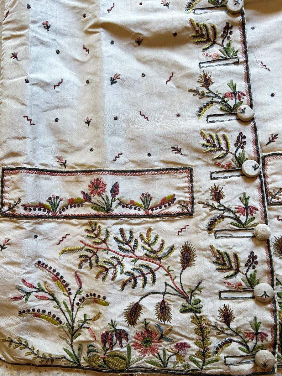 Circa 1785
France

Beautiful waistcoat of the Louis XVI period in cream taffeta embroidered with polychrome silk threads and silver threads. Straight cut, square, with two flap pockets and embroidered buttonholes with nine buttons covered in the