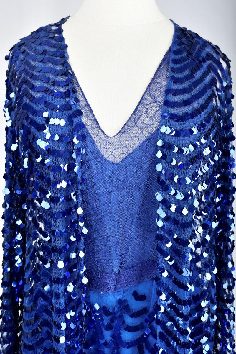 Circa 1930

France

Beautiful Haute Couture dress and jacket in lace and blue tulle embroidered with iridescent sequins, possibly Gabrielle Chanel. Sleeveless dress, square neckline with lavender blue lace bodice and matching belt with glass