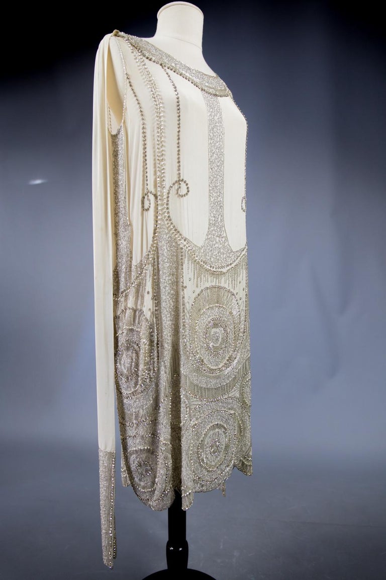 Circa 1925/1930

France

Beautiful ball gown called Charleston or Flapper dress Haute Couture unidentified ivory silk crepe embroidered and dating from the late 1920s. Dress with straight cut without sleeve with small neckline boat in front and