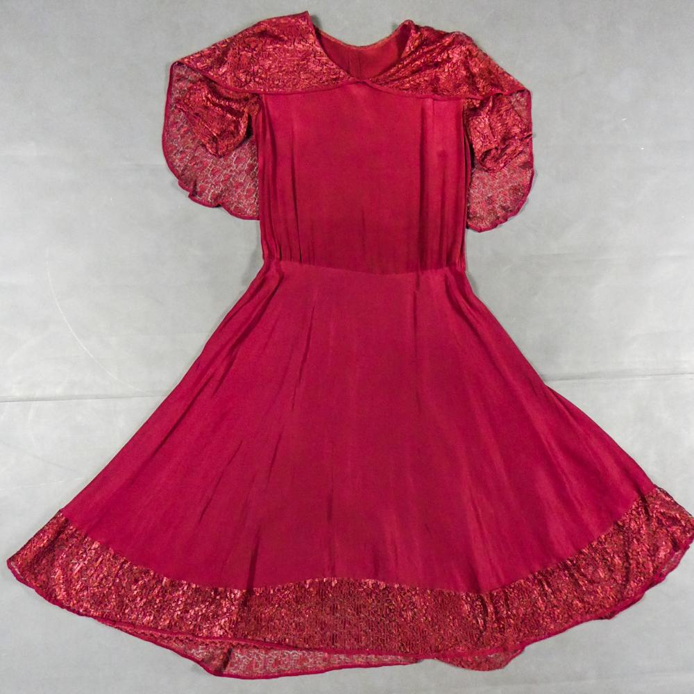 Circa 1935/1940
France

Elegant day dress in wine-red or burgundy silk crepe from the late 1930s. Loose dress with round collar and matching mechanical lace charms. The headcarf shawl collar drapes itself elegantly over the shoulders and back, the