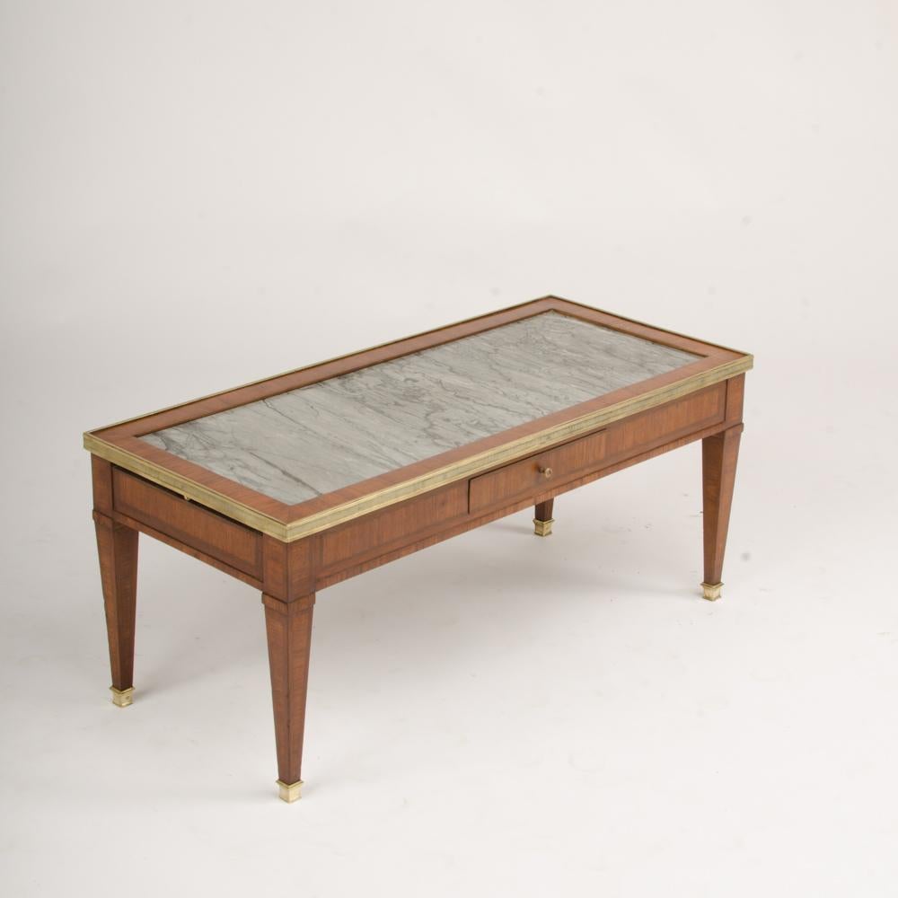 A French Directoire style mahogany coffee table C 1940, with grey marble top, one central drawer with two lateral extensions.