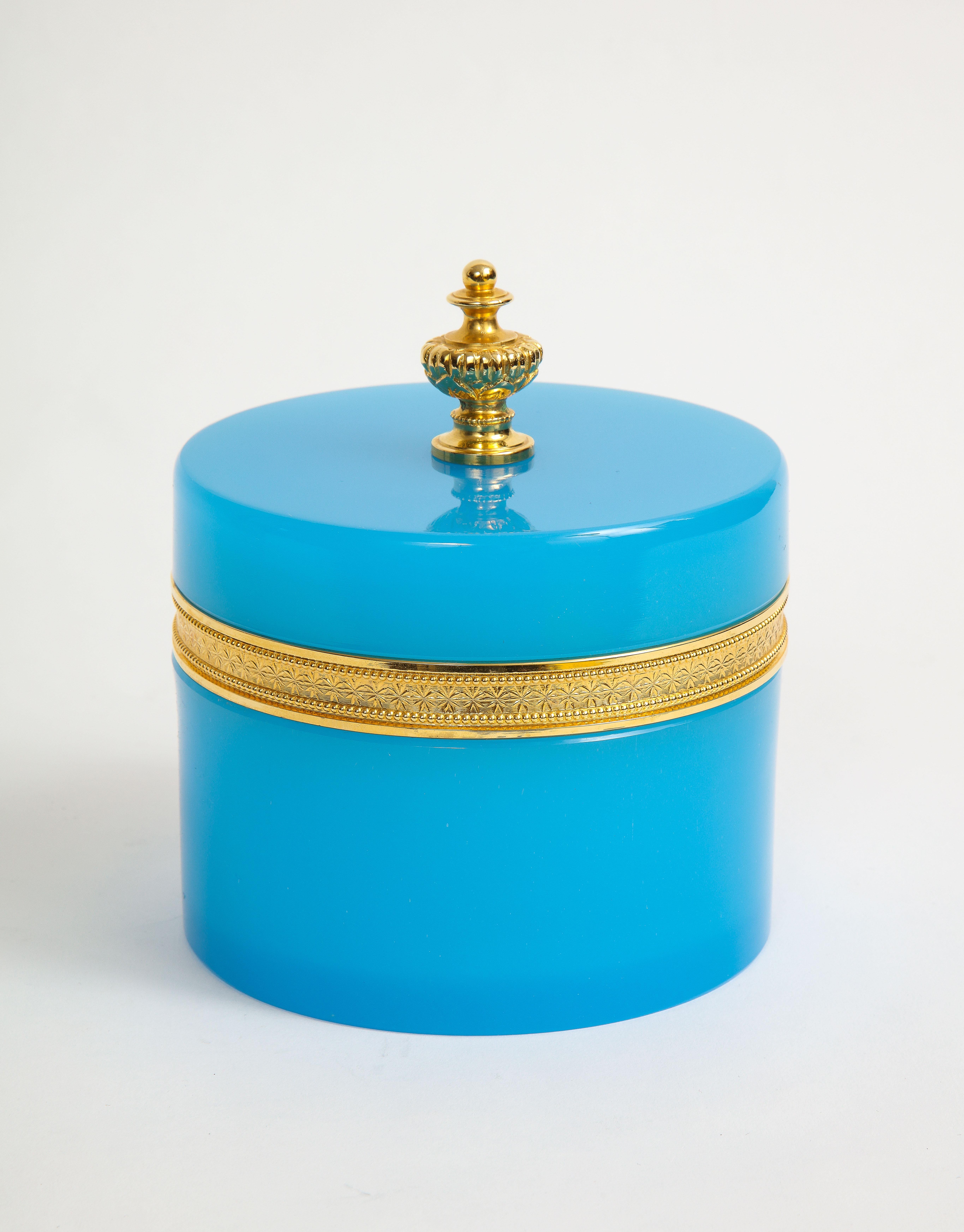 A French dore bronze mounted blue opalescent and dore bronze finial covered box. This round form box is very unusual with a blue opalescent color and dore bronze mount. The top is fitted with a dore bronze finial with is connected from the inside