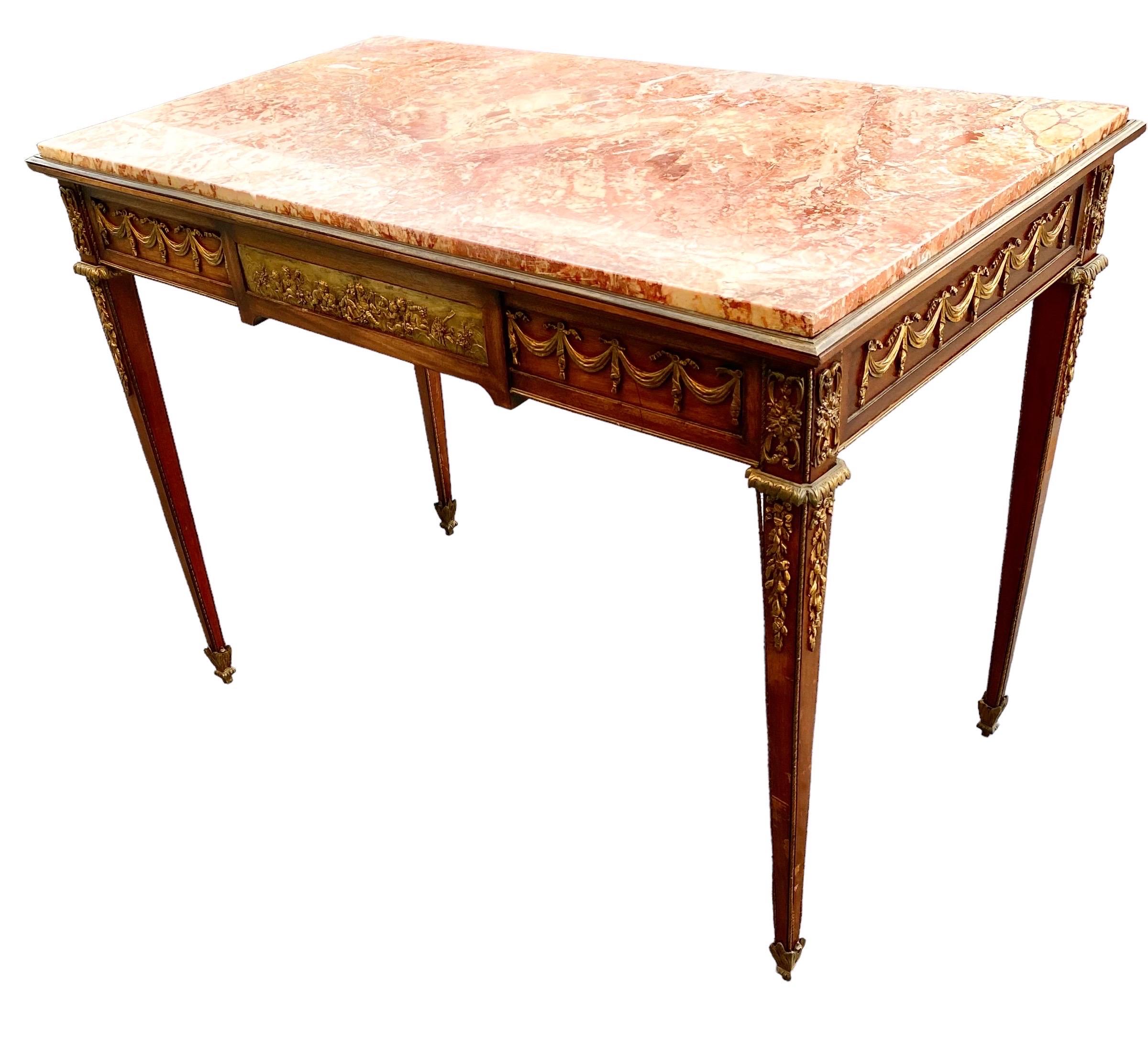 Une élégante table/bureau de très haute qualité du début du 20e siècle en acajou Louis XVI, bronze doré et marbre Arabescato au centre et sur le côté, attribuée à François Linke. La table repose sur des pieds circulaires fuselés et cannelés, avec