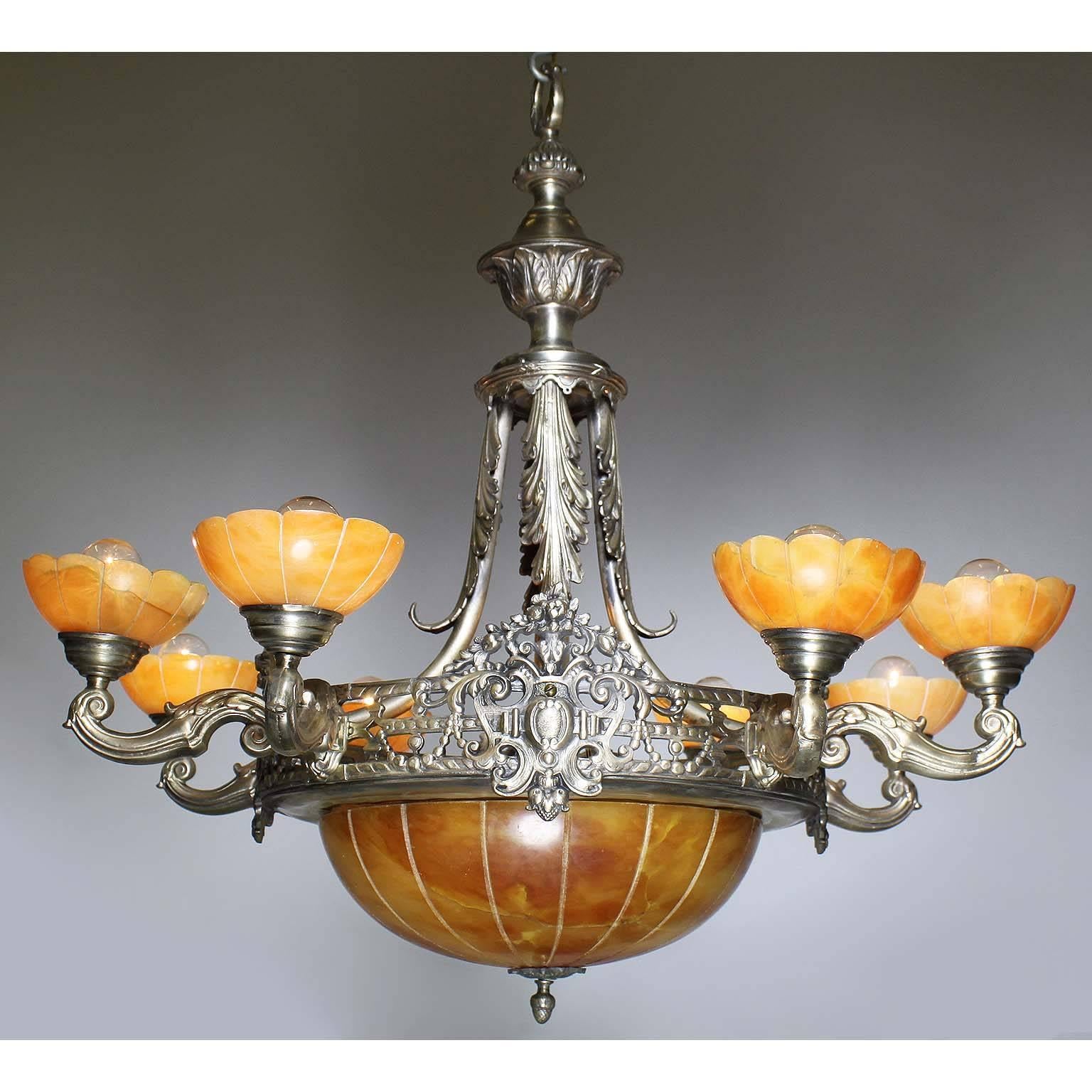 A French early 20th century Art Deco silvered bronze and carved caramel-color alabaster eight-light chandelier. The pierced silver plated bronze frame, suspended by four scrolled braces with acanthus decorations, surmounted by eight scrolled shaped