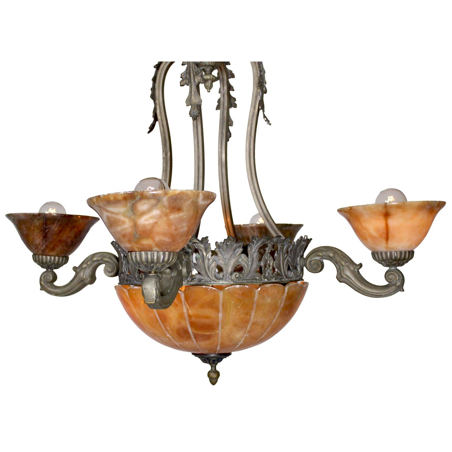 Araña francesa de cuatro luces de bronce plateado y alabastro tallado color caramelo de principios del siglo XX. El marco de bronce plateado perforado, suspendido por cuatro tirantes con decoración de acanto, está coronado por cuatro brazos de luz