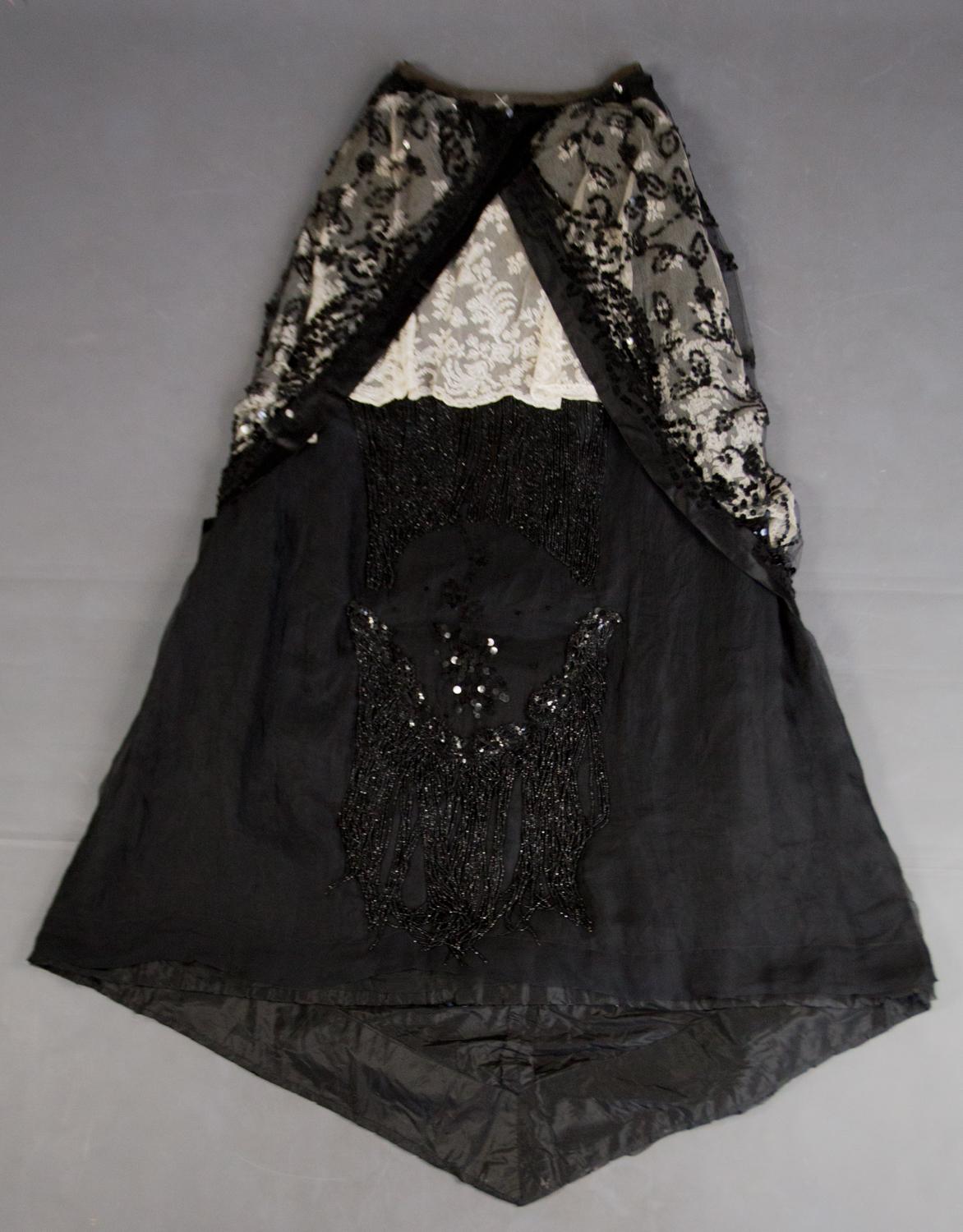 Circa 1900
France
 
Beautiful reception dress with Belle Epoque train, entirely embroidered with jet pearls and sequins on black chiffon and tulle and white embroidered tulle superimposed, playing with duotone. Dress in two parts, boned bodice