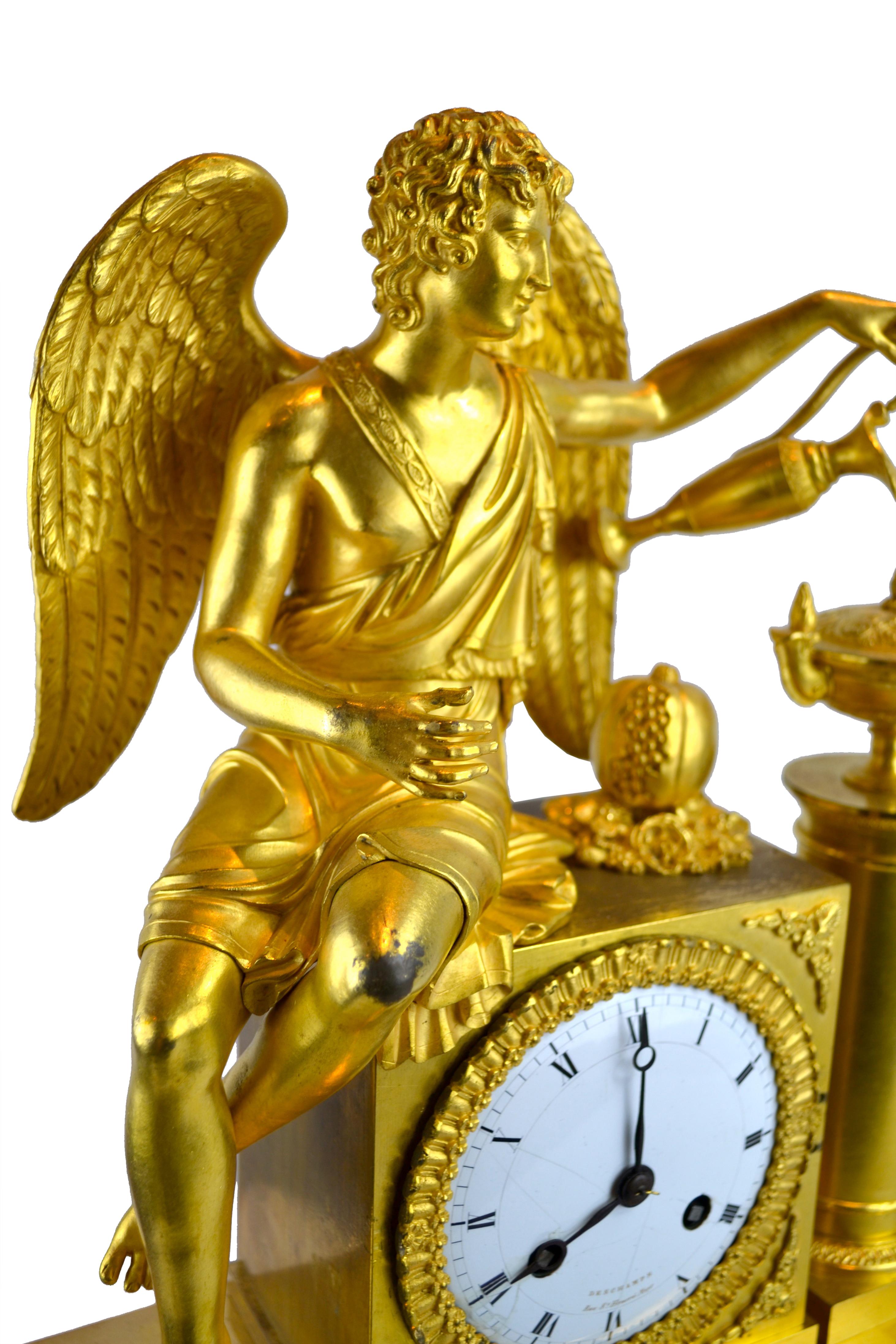 A figural French Empire clock in gilded bronze representing an allegory on how love nourishes life or “L’Amour alimentant la vie” in French. The clock shows a seated winged Amor refilling a lamp with oil, the symbol of life. The pomegranate placed