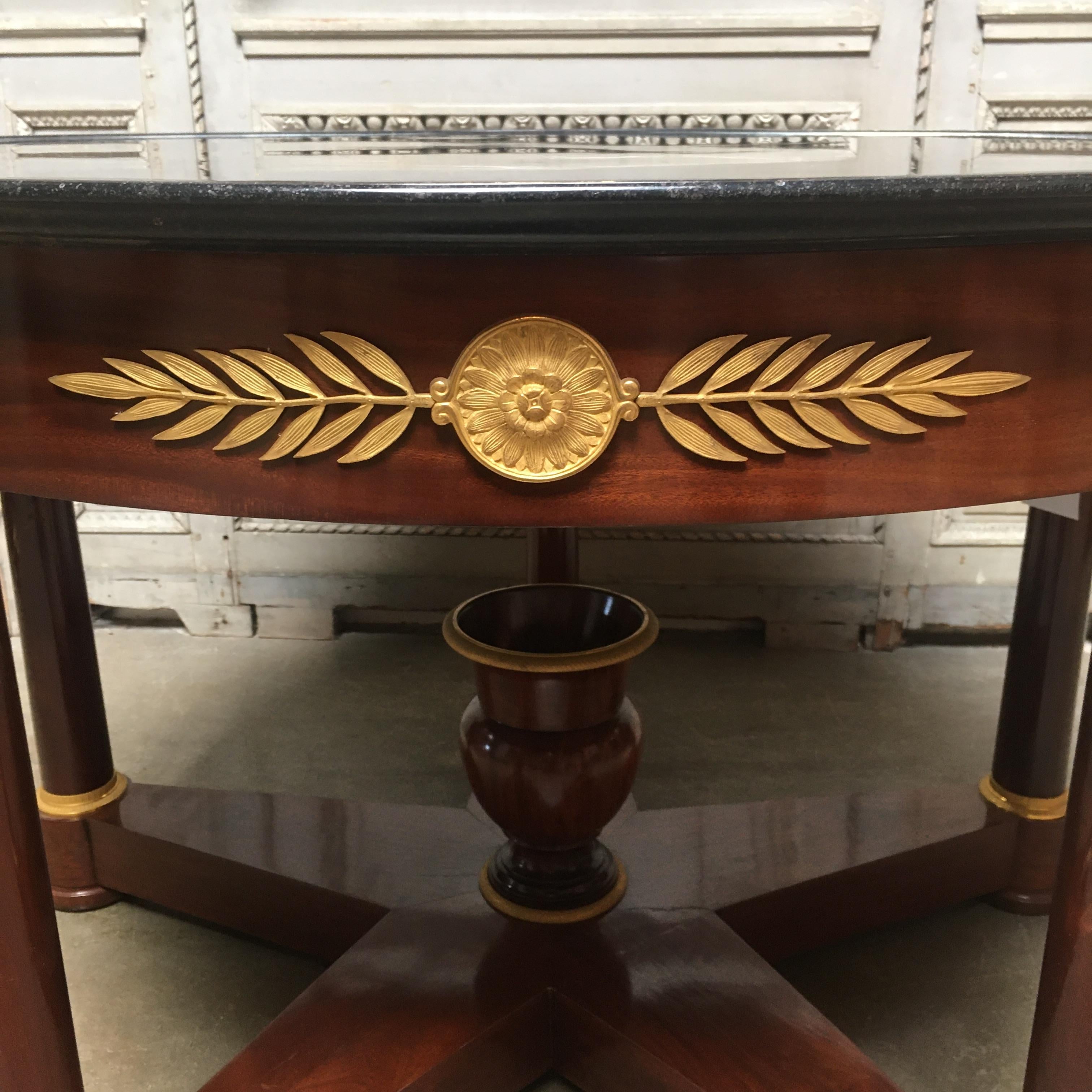 A French 19th Century Empire mahogany center table with bronze doré mounts and a marble top.  This handsome table features beautifully executed bronze pieces mounted throughout the apron and legs of the table. The Empire table has a center urn