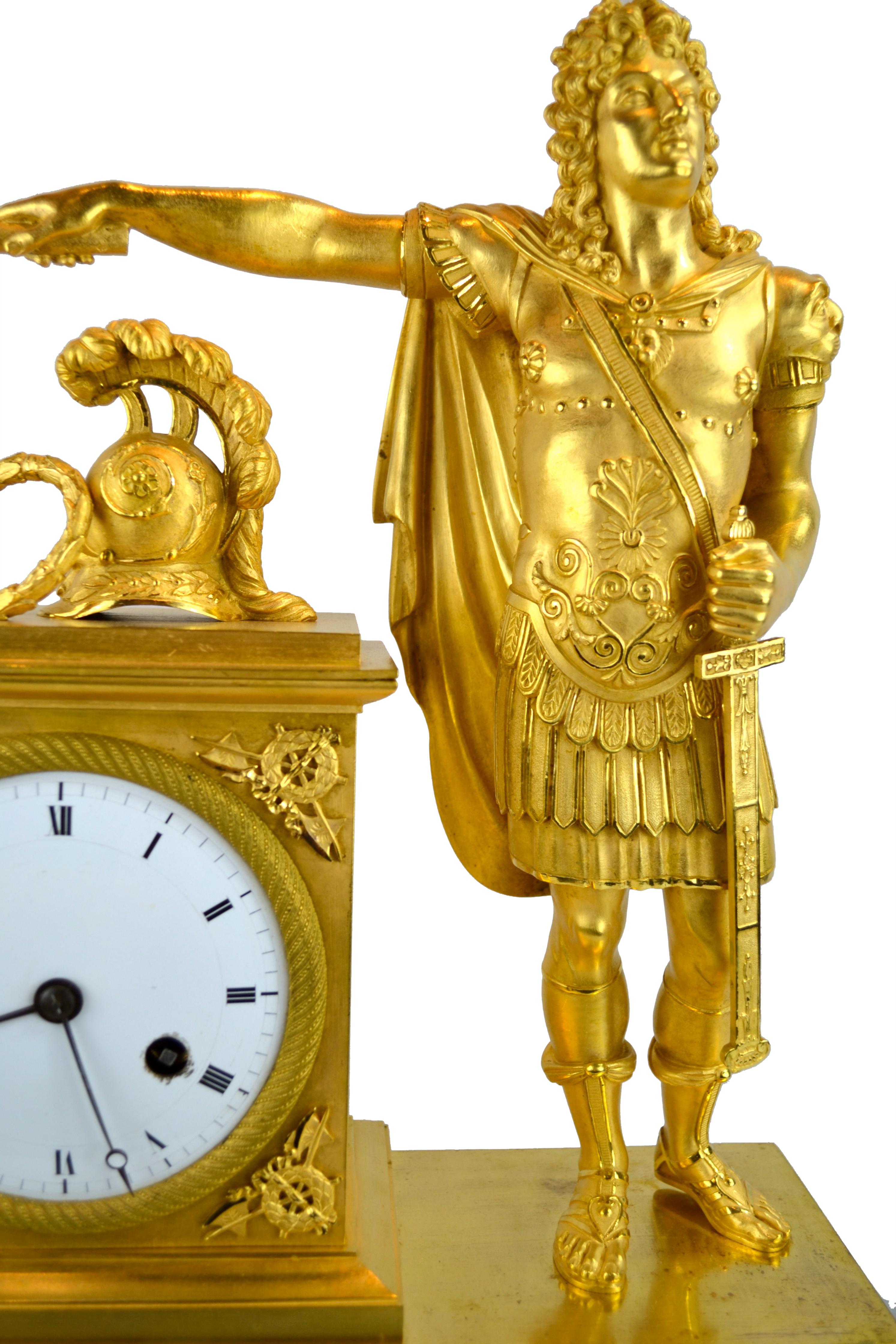 An early French Empire mantel clock depicting Louis XVI dressed as Caesar. The entirely fire gilt case depicts a standing figure of Louis XVI dressed as a Roman emperor (Caesar), holding a scroll in his outstretched right arm over the plinth which