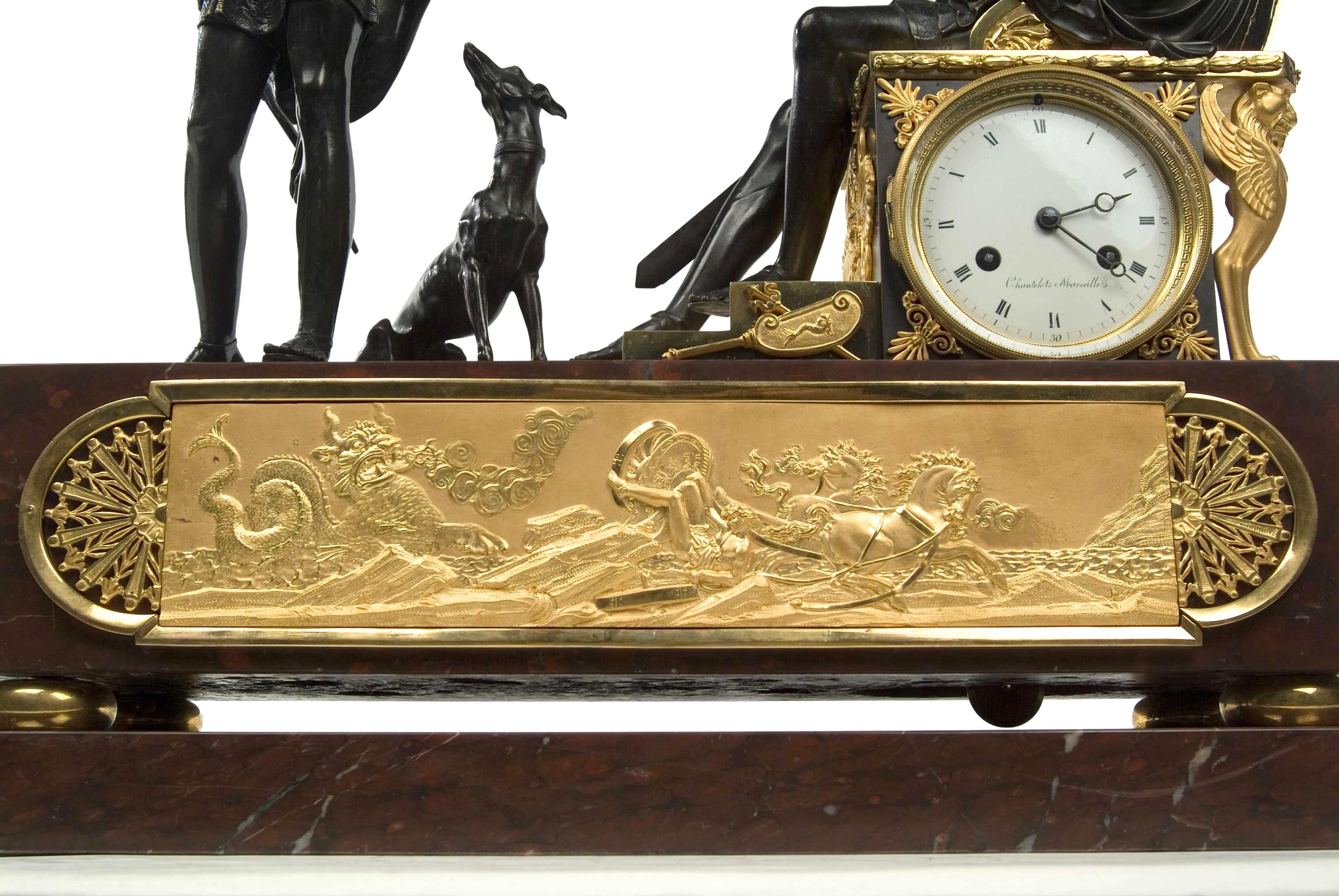 A rare piece of French Empire decorative art; a mantel clock in gilt and patinated bronze on a double plinth of red griotte marble. The clock tells the story of Theseus, seated on a throne, questioning Hippolytus about his incestuous relations with