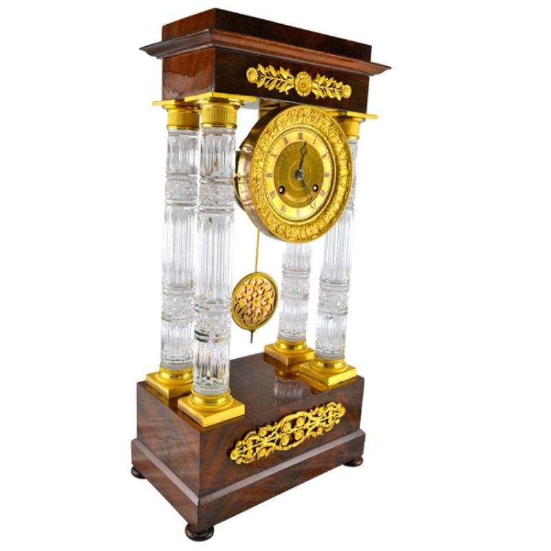 A rare example of a late French Empire portico clock combining the use of mahogany casing with gilt bronze mounts and cut crystal. The four pillars linking the top and bottom sections of the clock are made of finely cut crystal and have original