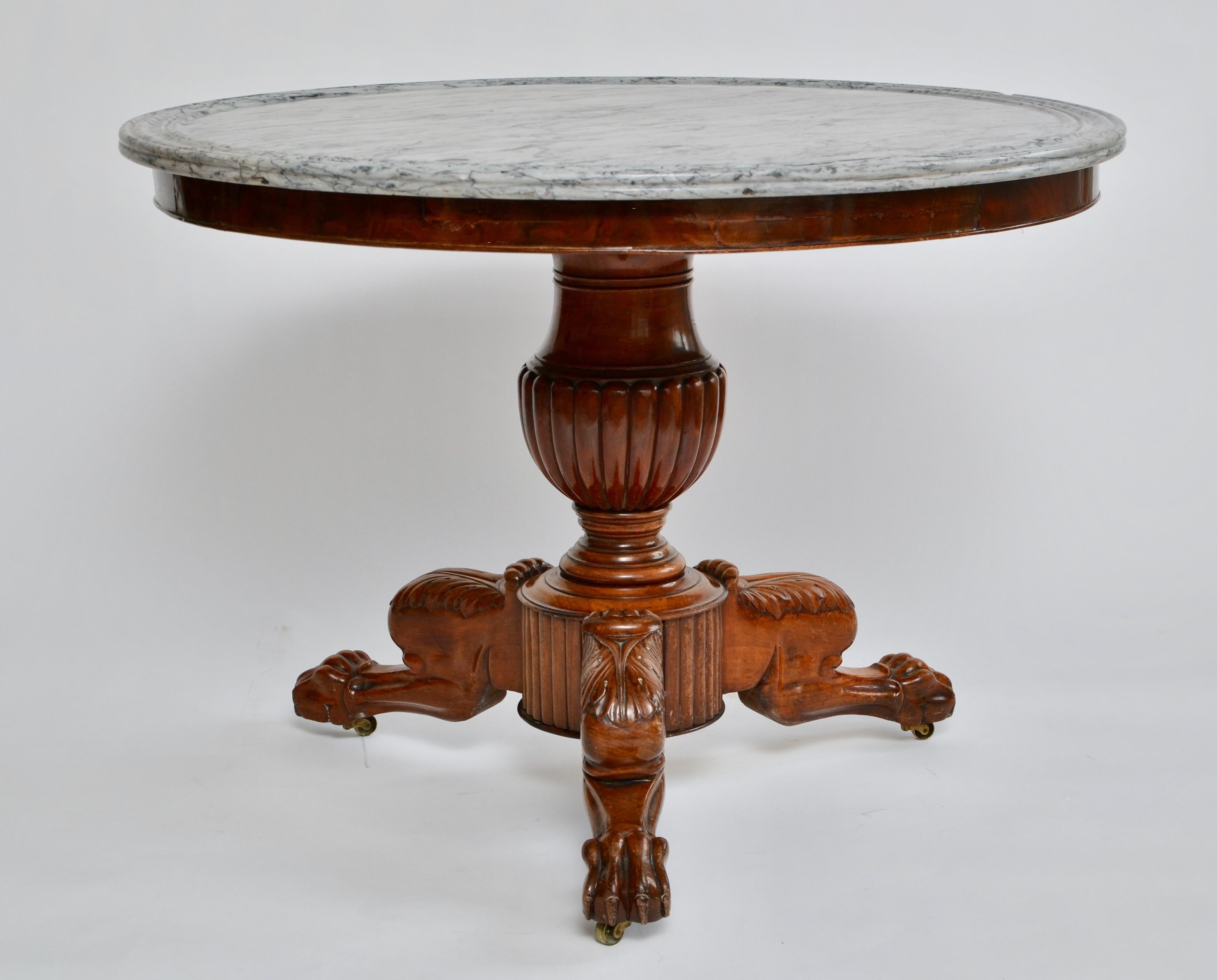 An early 19th century French empire mahogany gueridon table with a circular moulded grey marble top raised on an urn-form pedestal ending with acanthus carved tripod legs terminating in lions paw feet with castors. Very nice carving.
