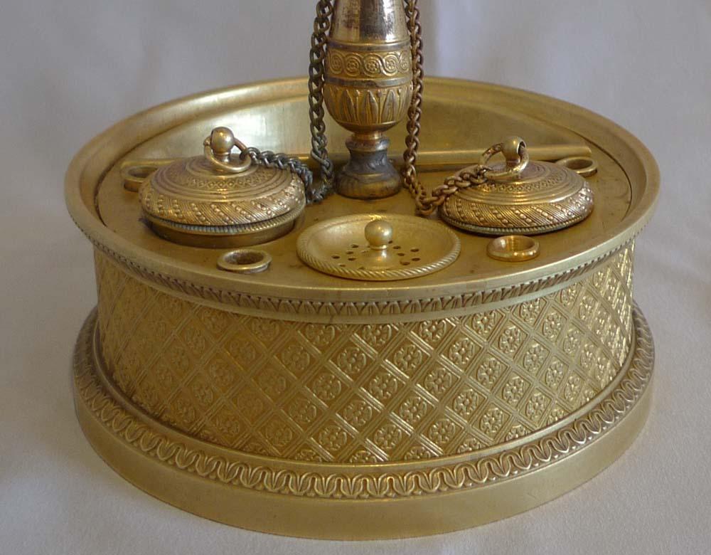 Un raffinato standish da scrivania in ormolu dell'Impero francese. Poggiato su una base circolare con modanature superiori e inferiori con decorazioni a foglie e dardi. Lo spazio intermedio è decorato con fiori all'interno di un motivo a diamante.