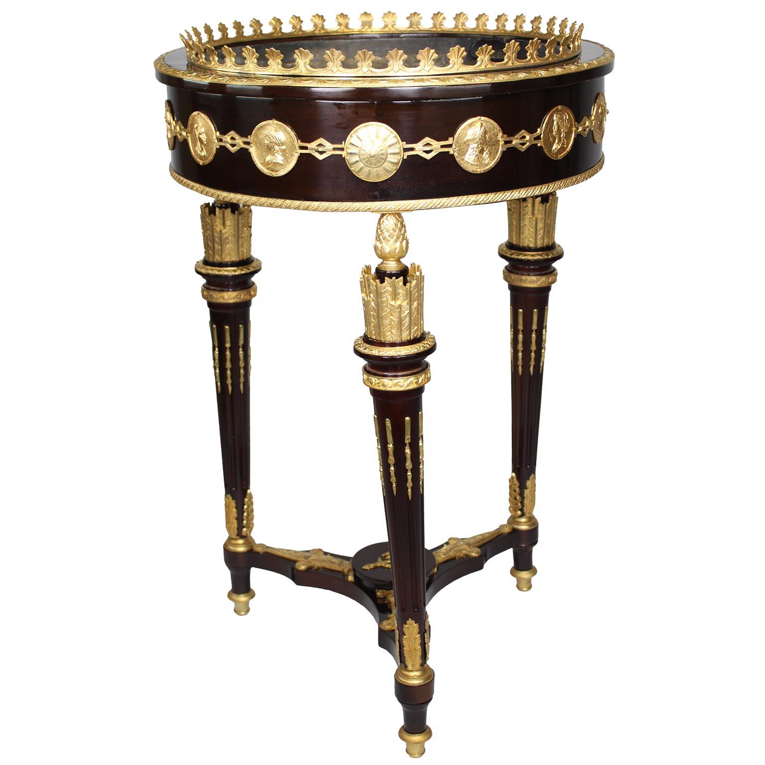 A Fine French Empire Revival Style Late 19th/Early 20th Century Mahogany and Gilt-Bronze Mounted Planter or Jardiniere. This elegant circular planter features a mahogany structure adorned with gilt-bronze mounts. The top is surmounted by allegorical