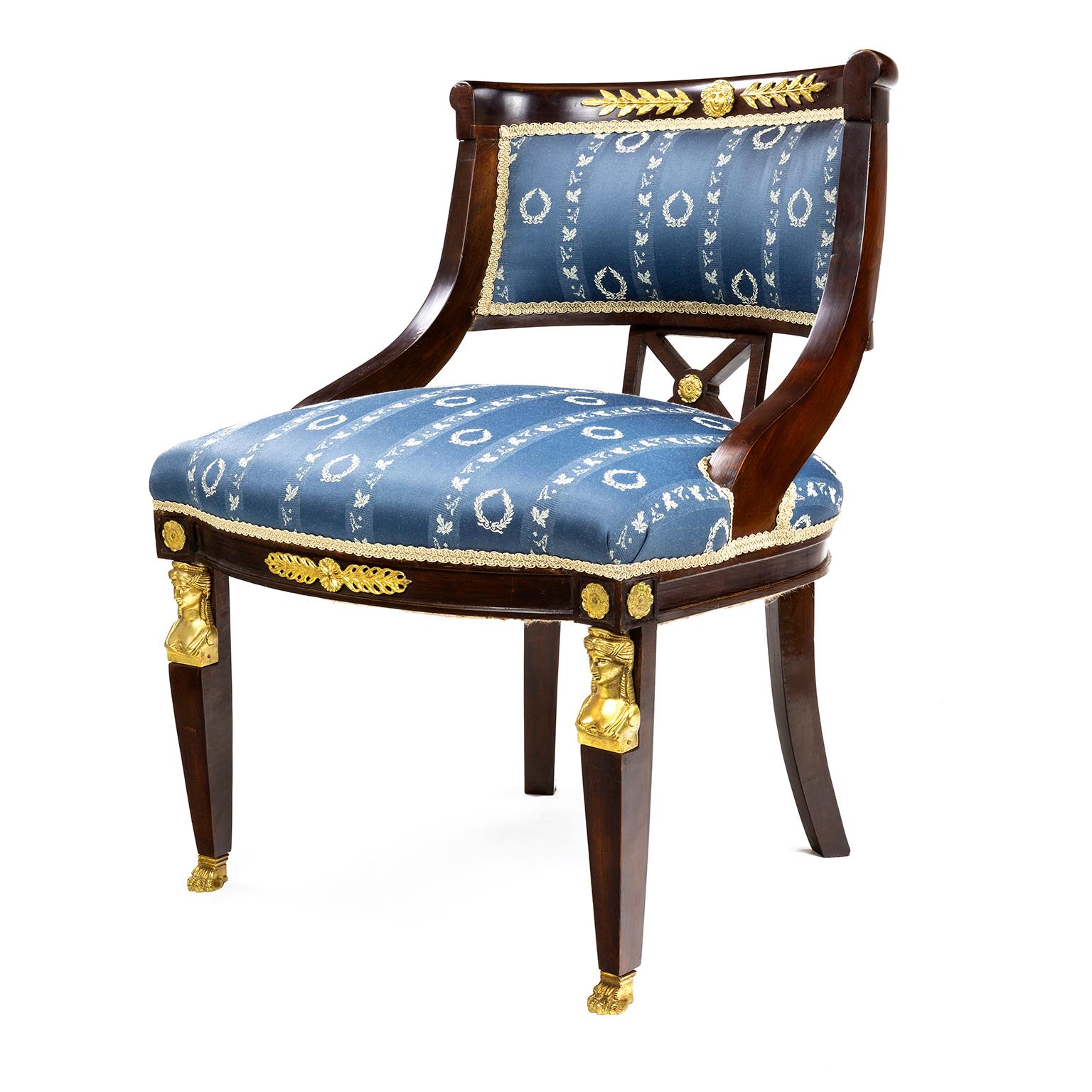 A French 19th century Empire style chair in mahogany with brass laurel wreaths, with brass anthemion mounts below brass rosetts at the top of the tapering front leks, down to brass feet with outswept legs to the backs.

The chair is in very good