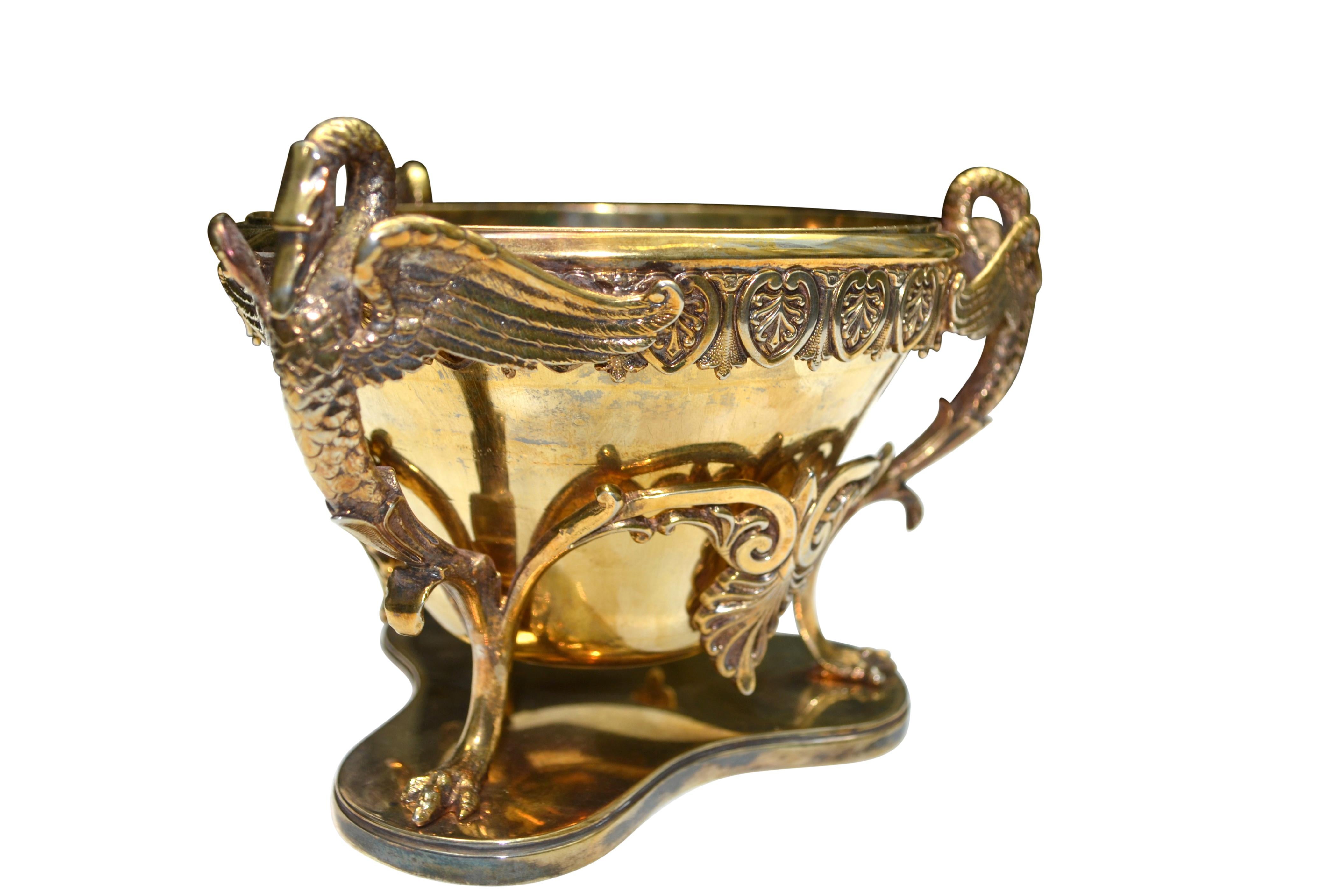 A French Empire style gilded metal bowl with a removable silvered bronze bowl sitting in a gilded silver base with acanthus decoration around the rim and elaborate swan heads supported by a tri-form base.