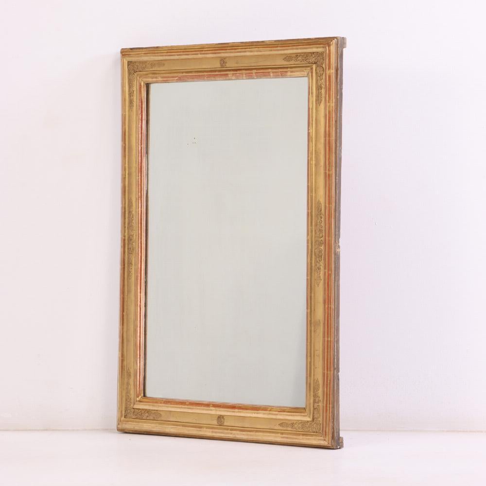 A stately French mirror featuring a carved giltwood and gesso frame with classical corner detailing. This mirror reflects the grandeur and symmetry characteristic of the Empire aesthetic, making it a distinguished addition to traditional or eclectic