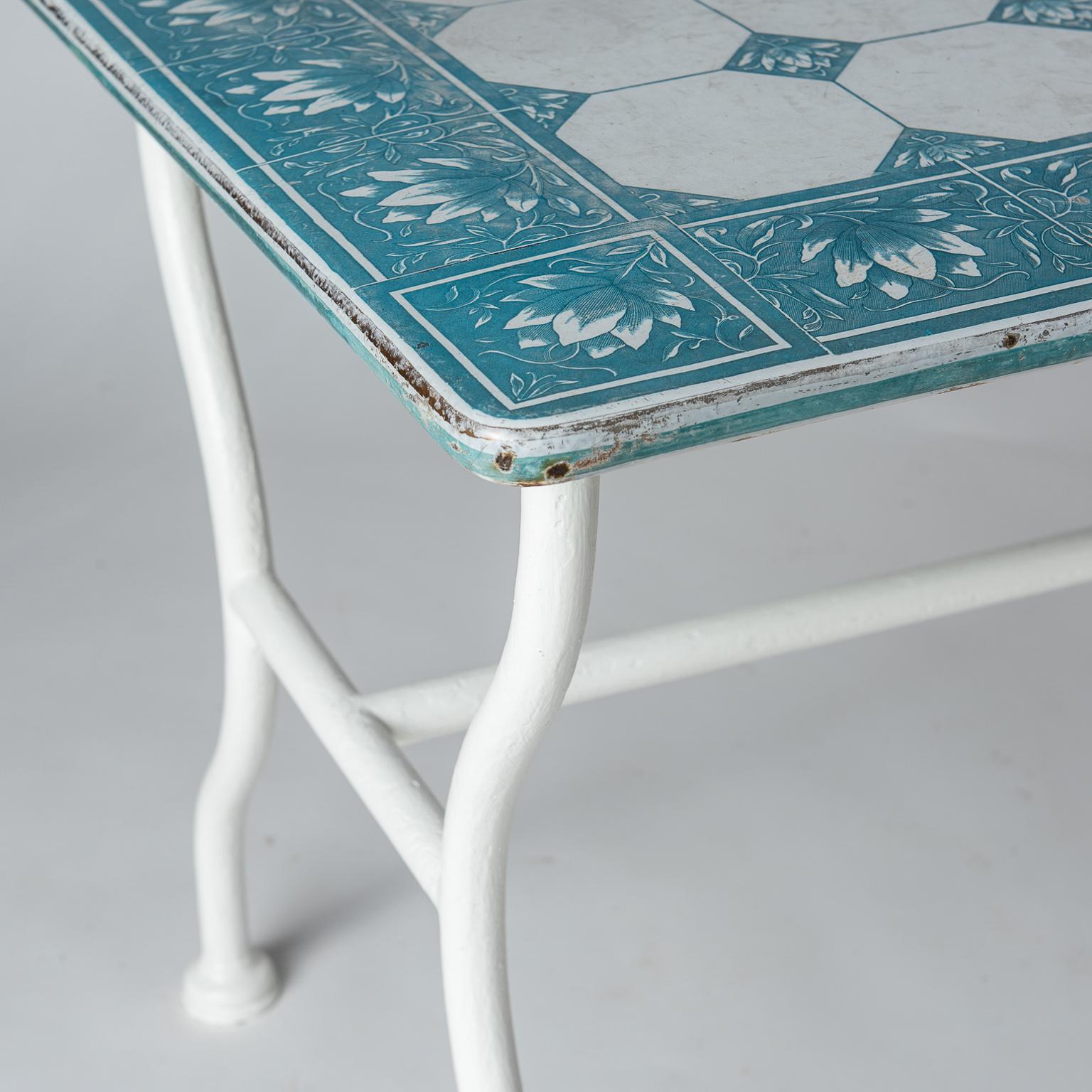 This charming table has an enamel top of blue and white flowers in a pattern of squares made to look like tiles. The base is made of white painted tubular metal. It was most probably part of the decor in a florist shop somewhere on the Cote D’azure,