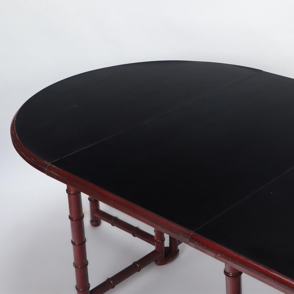 Table de salle à manger française en faux bambou, à la manière de Jansen, C.C 1960. La table à plateau stratifié extensible peut accueillir jusqu'à cinq feuilles, le tout soutenu par une base en bois tourné. Certains des battants sont dotés d'un jeu