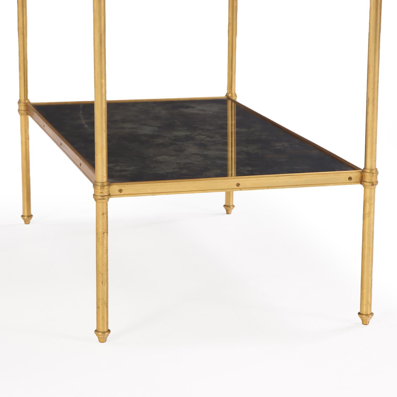De bonne taille et de bonne proportion, la table comporte deux étagères en miroir moucheté, soutenues par un cadre en laiton doré. Le design est sobre mais élégant, reflétant le style néoclassique favorisé par la Maison Jansen et d'autres grands