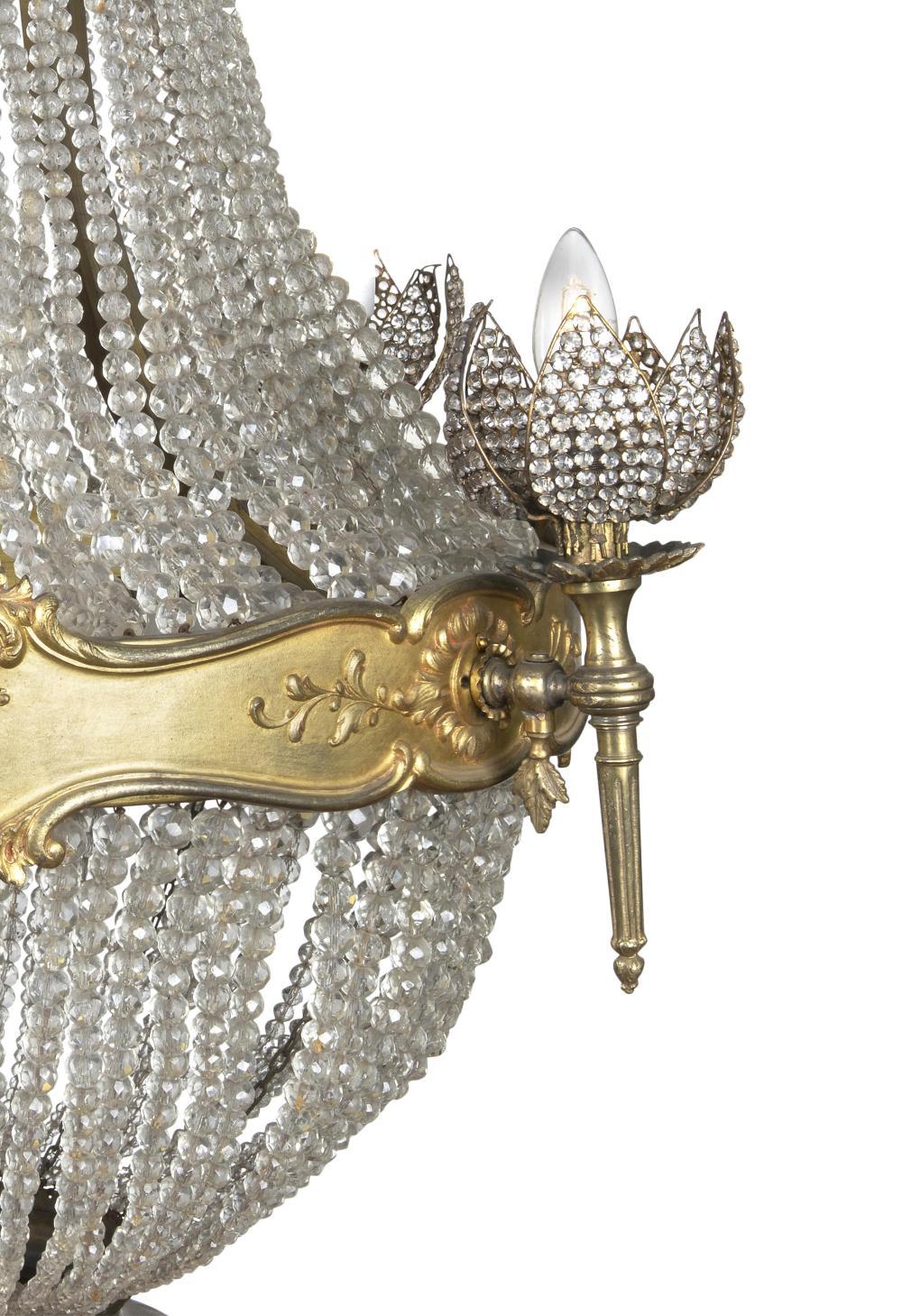 Lampadario a cestello francese in bronzo dorato e vetro, XIX secolo

Provenienza: Collezione privata australiana.

Descrizione: 
Lampadario a tenda e a sacco, con corona decorata da un fregio di volute a C e catene di perline che scendono fino alla