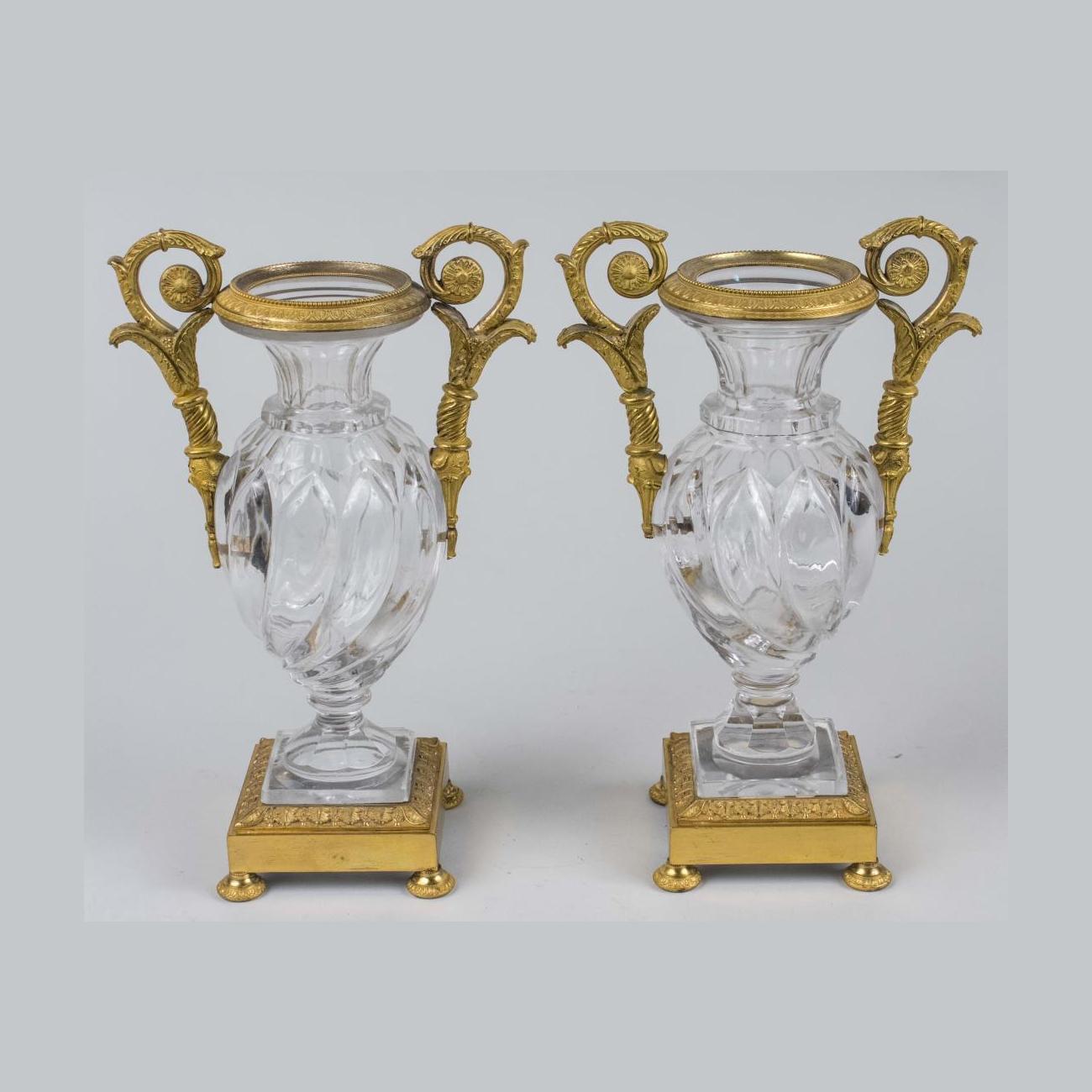 An elegant French gilt-bronze and glass clock garniture.
Urn shaped gilt bronze mounted crystal clock with enamel chapter ring with Roman numerals, decorated with a pair of female term figures, together with a pair of matching urns.

Date: 19th