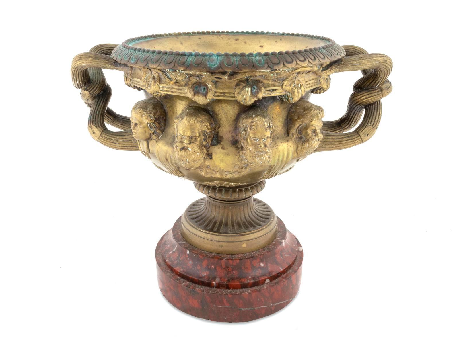 Französische Warwick-Vase mit zwei Henkeln aus Goldbronze
Nach Clodion. Mit Ei-und-Pfeil-Rand, das Gefäß in Relief mit Puttenköpfen und verschlungenen Griffen in Form von Zweigen, auf einem runden Sockel aus Marmor Rouge Griotte, um 1880
Maße: