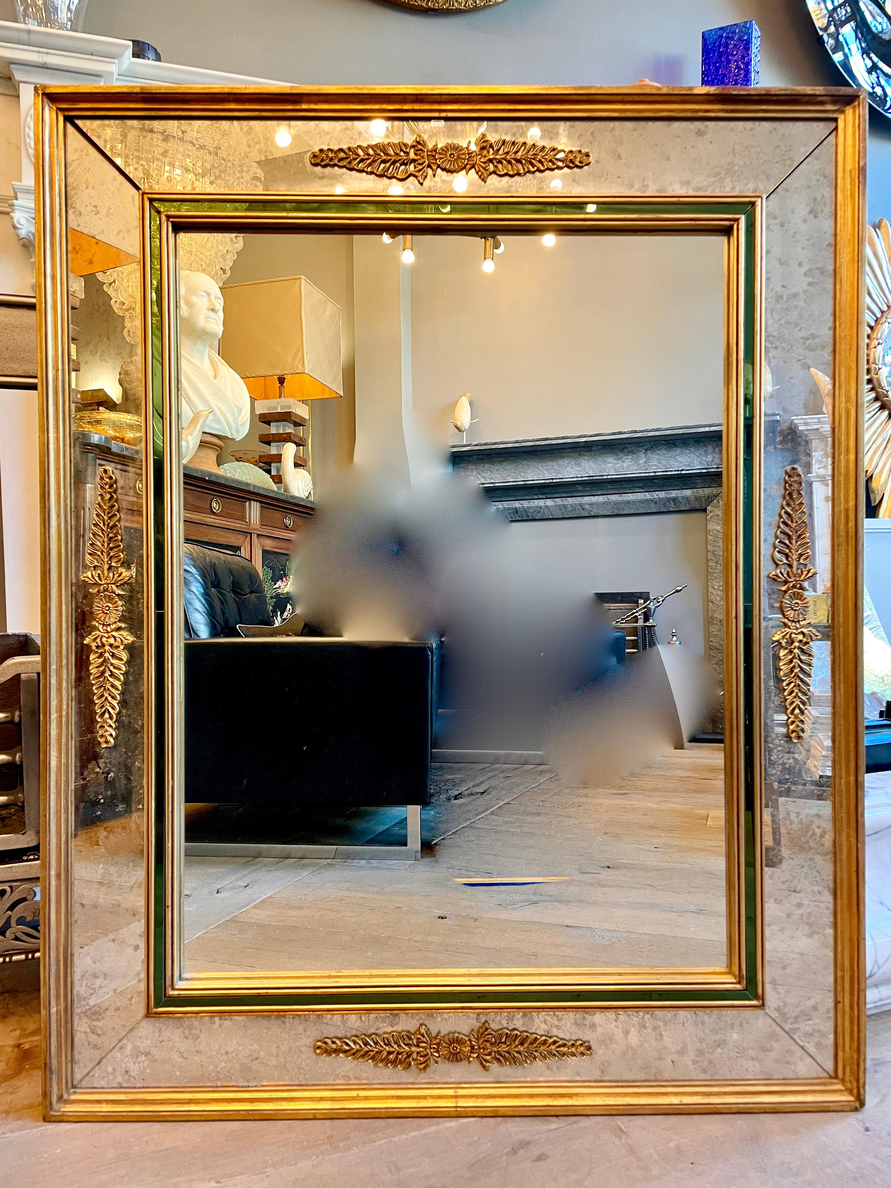 A panelled French mirror with outer border in distressed mirror with an emerald green mirrored slip inner framing a large mirror plate. All edged in gold gilt with borders and stylised gilt accents applied to outer panels. 

French 

Circa 1970.