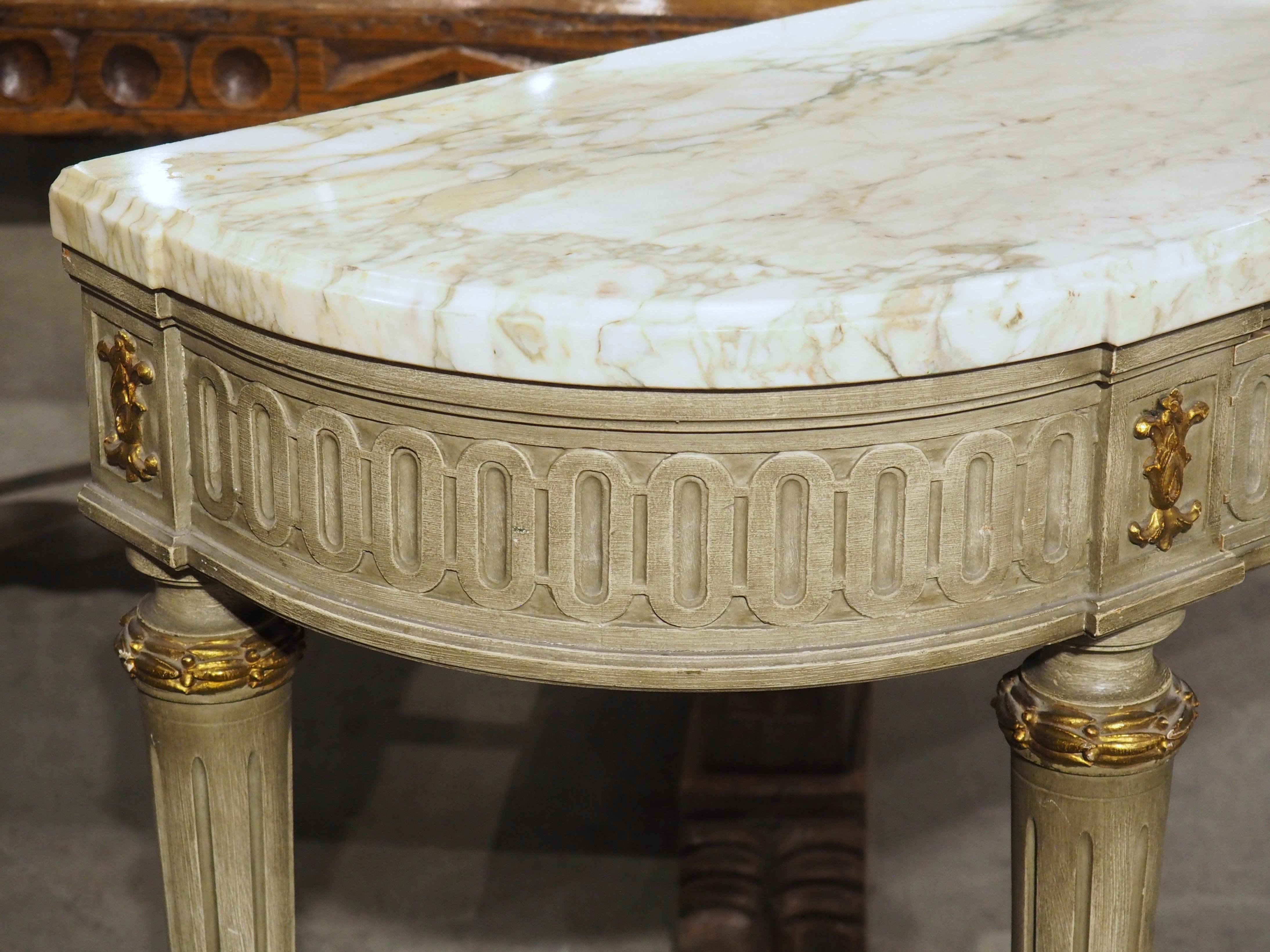 More information coming soon…

Hand-carved in the style of Louis XVI, this French demi-lune console table is topped by a cream marble with green and white inclusions.  The base has been hand-painted in a similar palette, consisting of a beautiful