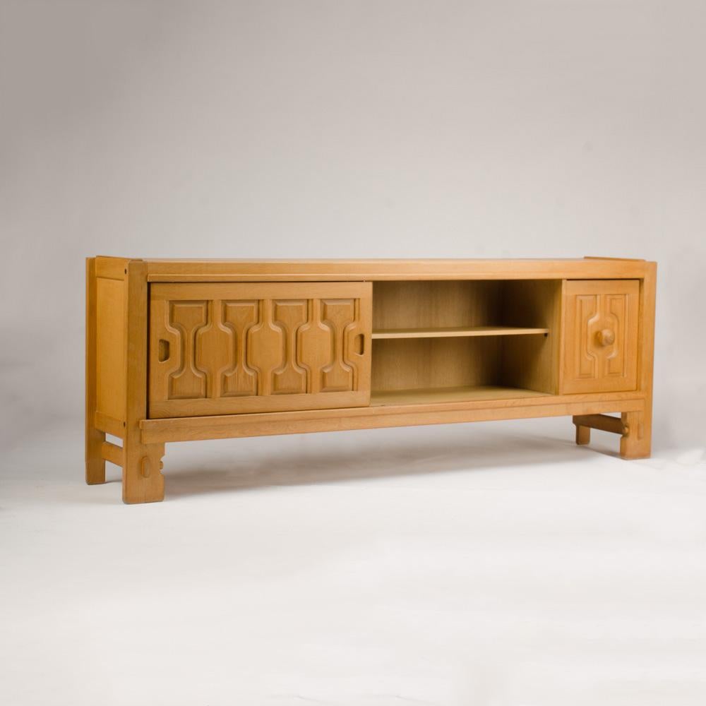 An imposing oak Guillerme et Chambron designed sideboard which features a geometric structure on the front side with two sliding doors opening to a large space for storage and wine drawer. Bold and sculptural.