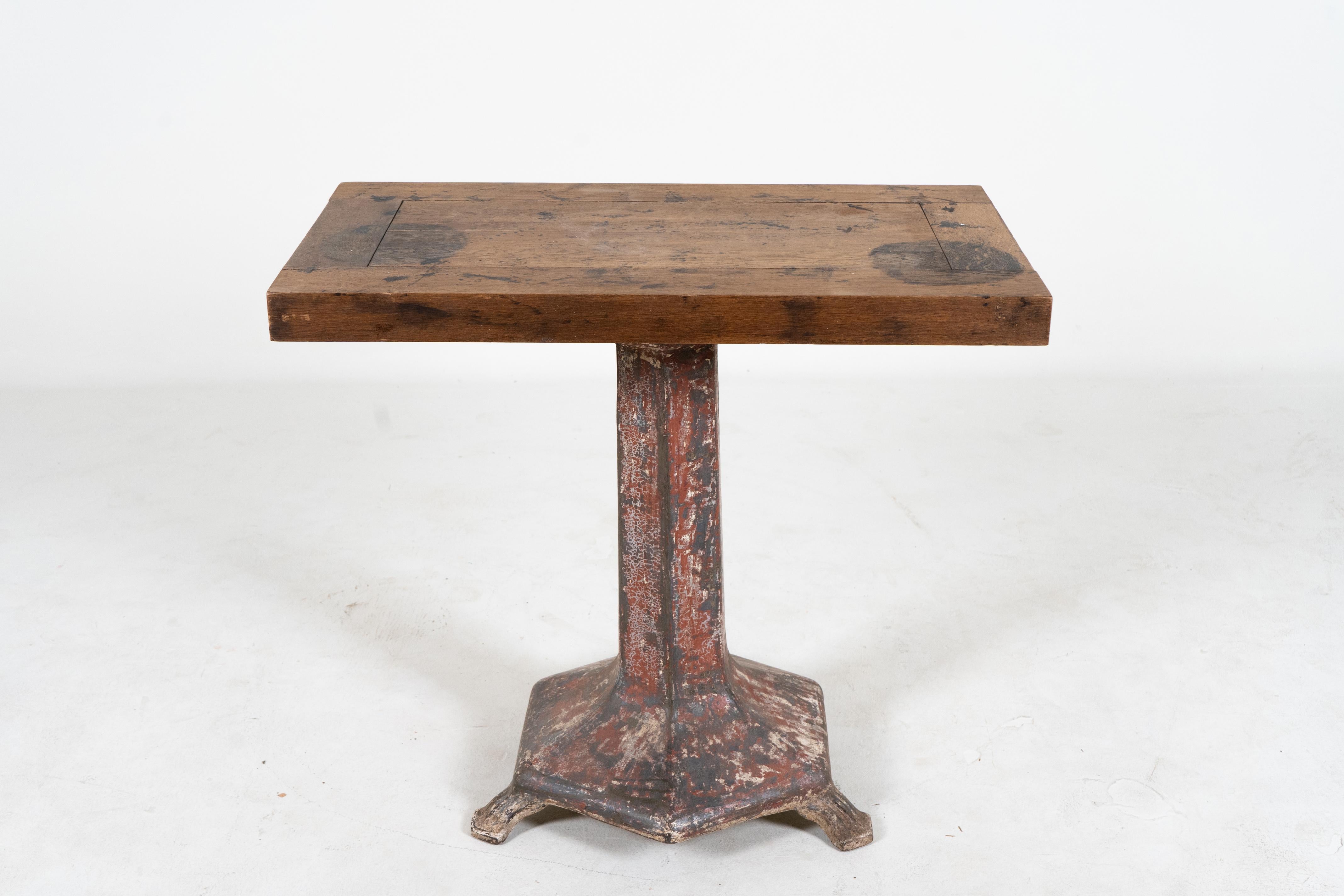 This unusually thick and sturdy oak table rests on a heavy iron base. It was used in a garment factory and the lack of corner legs allowed full movement and avoided snags. The top is quite smooth, very heavy and covered in minor scratches, stains