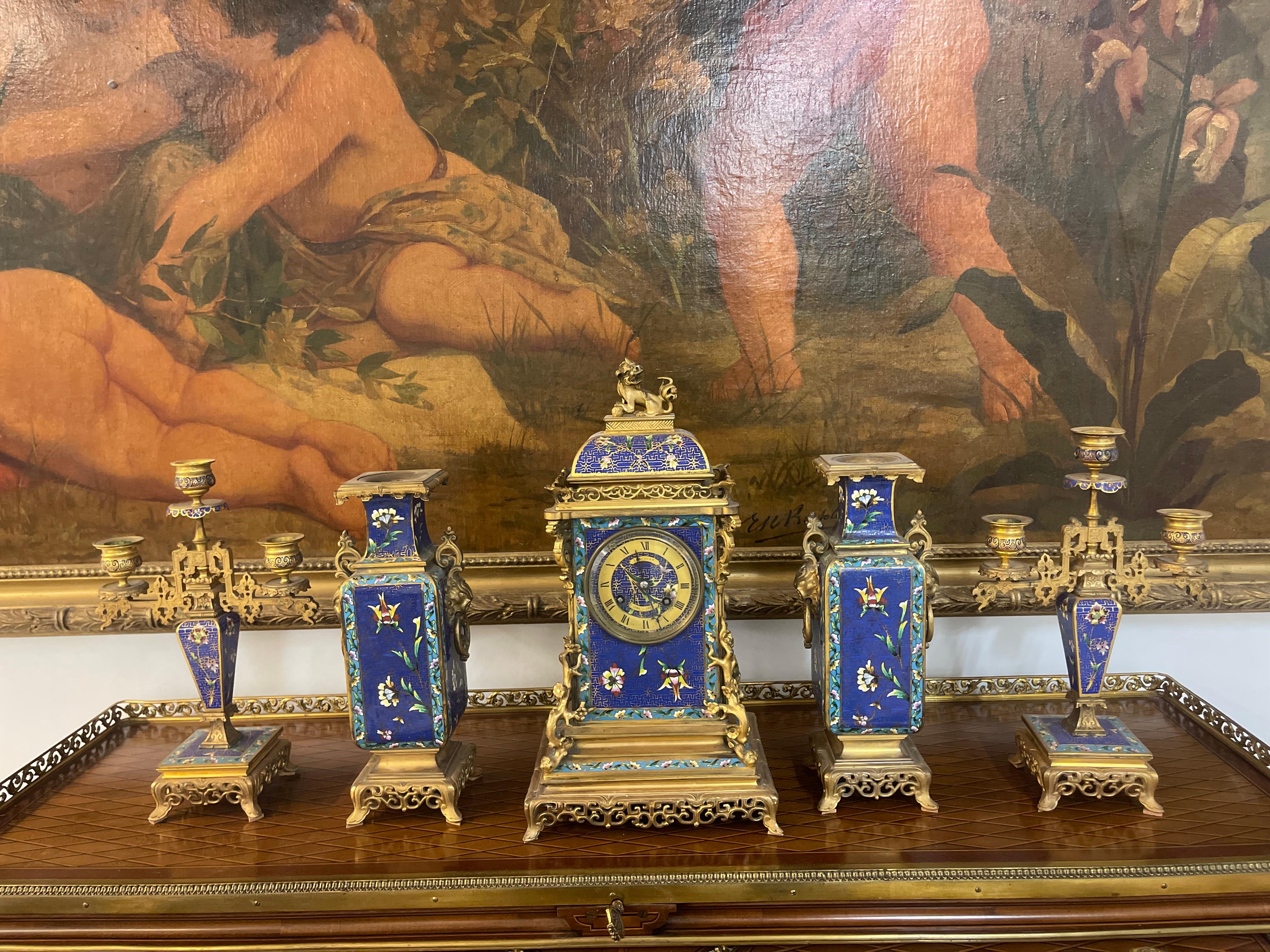 A French Japonaise Ormolu & Champleve Enamel Five-Piece Clock Garniture
France, Circa 1860
Comprising a mantel clock, a pair of vases and a pair of three-light candelabra, each with blue and turquoise ground and decorated with tropical flowers,
