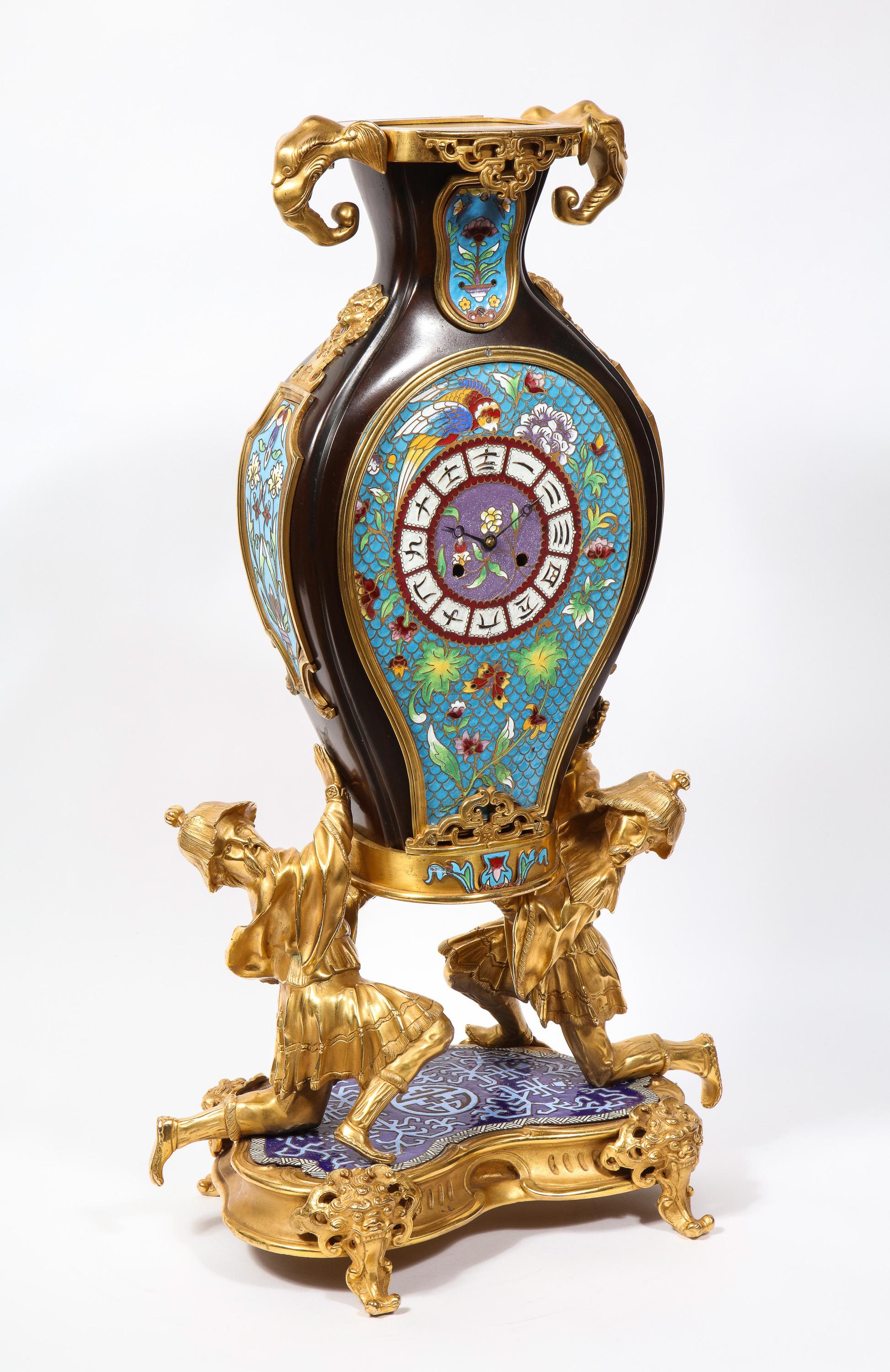 A French Japonisme Chinoiserie Ormolu, patinated bronze, and cloisonne enamel mantel clock, Attributed to Escalier De Cristal and Edouard Lievre, Paris, late 19th century.

Formed as a cloisonne enameled vase, with two Chinoiserie bronze men