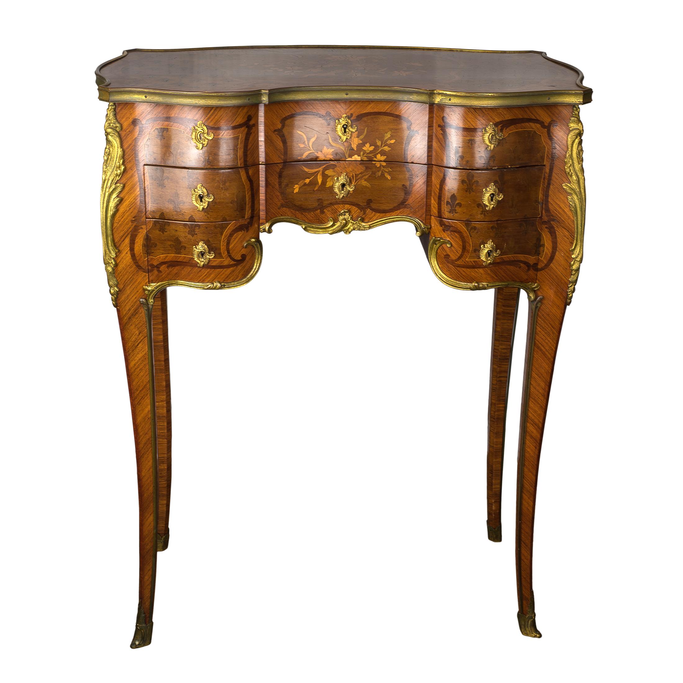 An exquisite kingwood and mahogany-veneered ormolu-mounted dressing table by Paul Sormani. The shaped top with floral inlay opens to fabric-lined compartment with mirror, sides with overall fleur-de-lis pattern, three faux drawers and three working