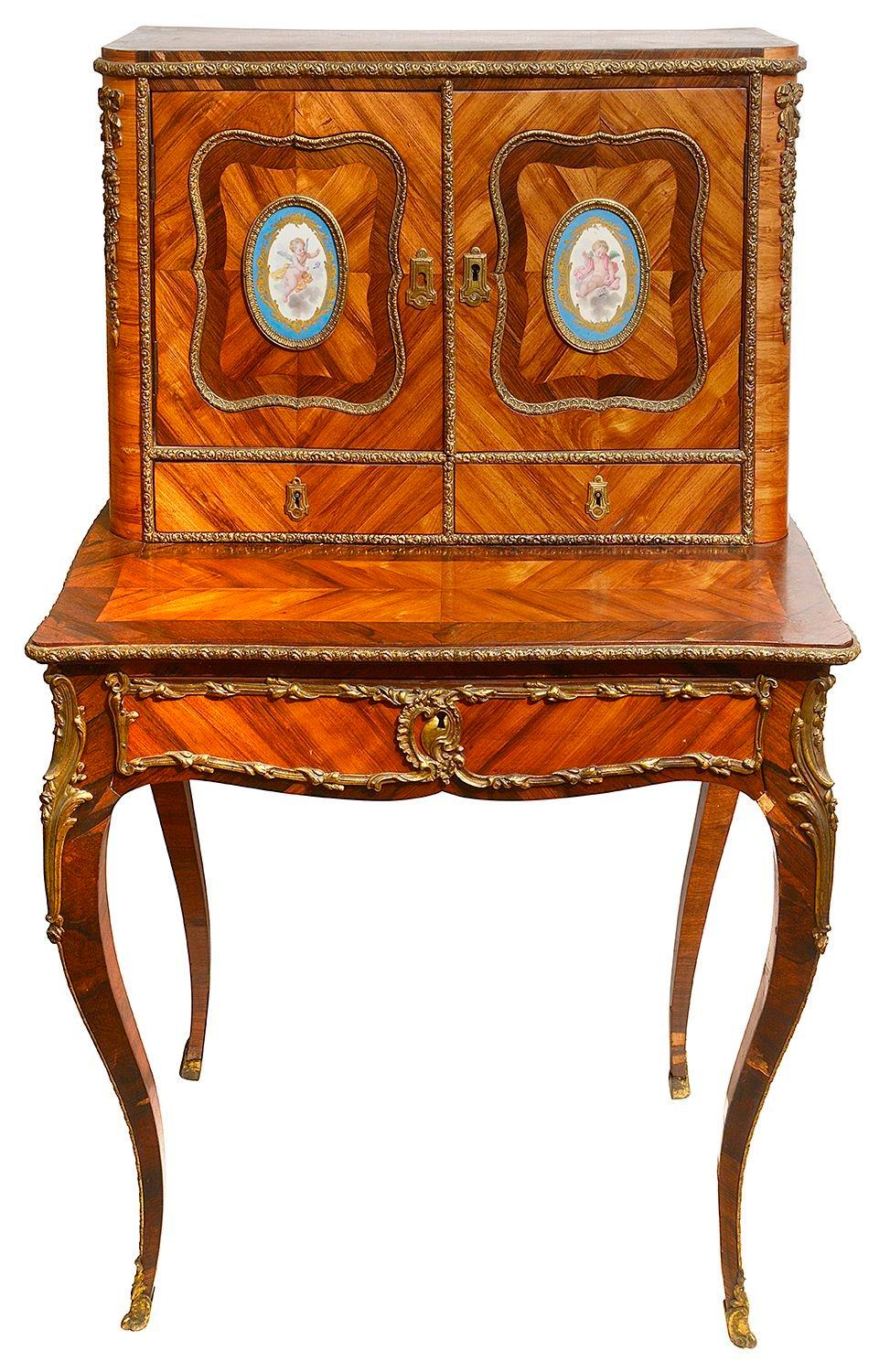 A French kingwood quarter veneered and ormolu-mounted bonheur du jour with Sevres-style oval floral plaques inset to the cupboard doors, two drawers to the upper section and a drawer to the frieze, raised on elegant cabriole legs with sabots feet,