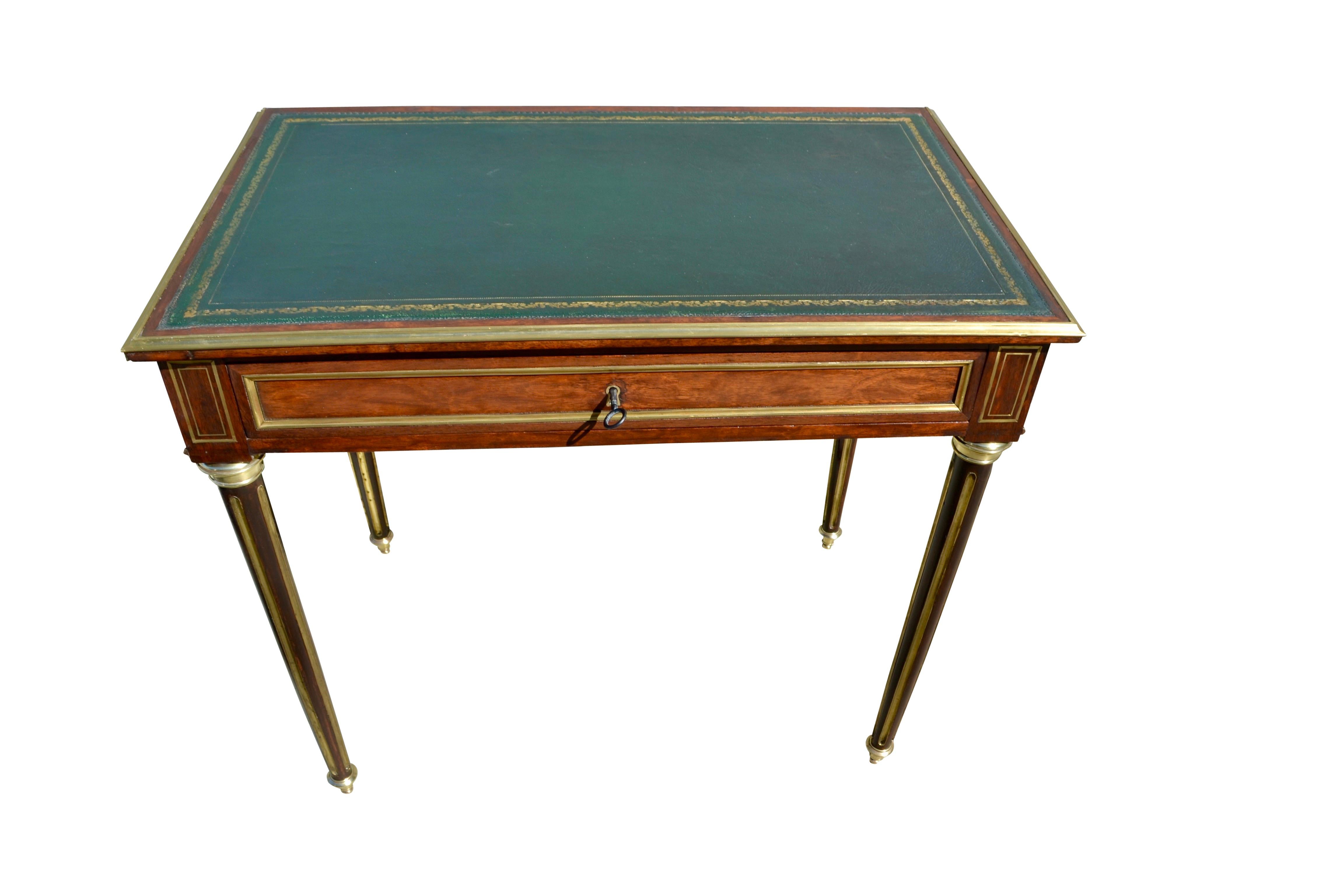A late 19 century French Louis XVI style writing table and console. The mahogany table has a green tooled leather top bordered in gilt bronze trim above a single mahogany lined drawer with its original lock and key. There is further decorative brass