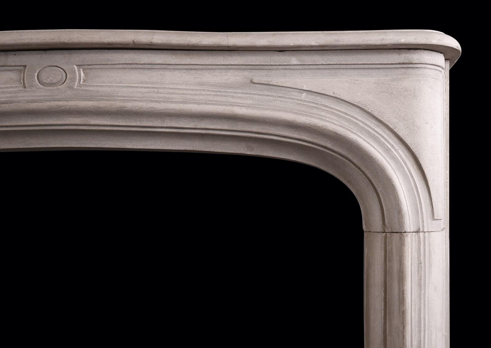 Un grazioso camino francese in pietra in stile Louis XIV. Gli stipiti sagomati e pannellati con patere ovali al centro sono sormontati da un fregio ad arco pannellato. Mensola modellata sopra. Di dimensioni ridotte, si adatta bene a una camera da