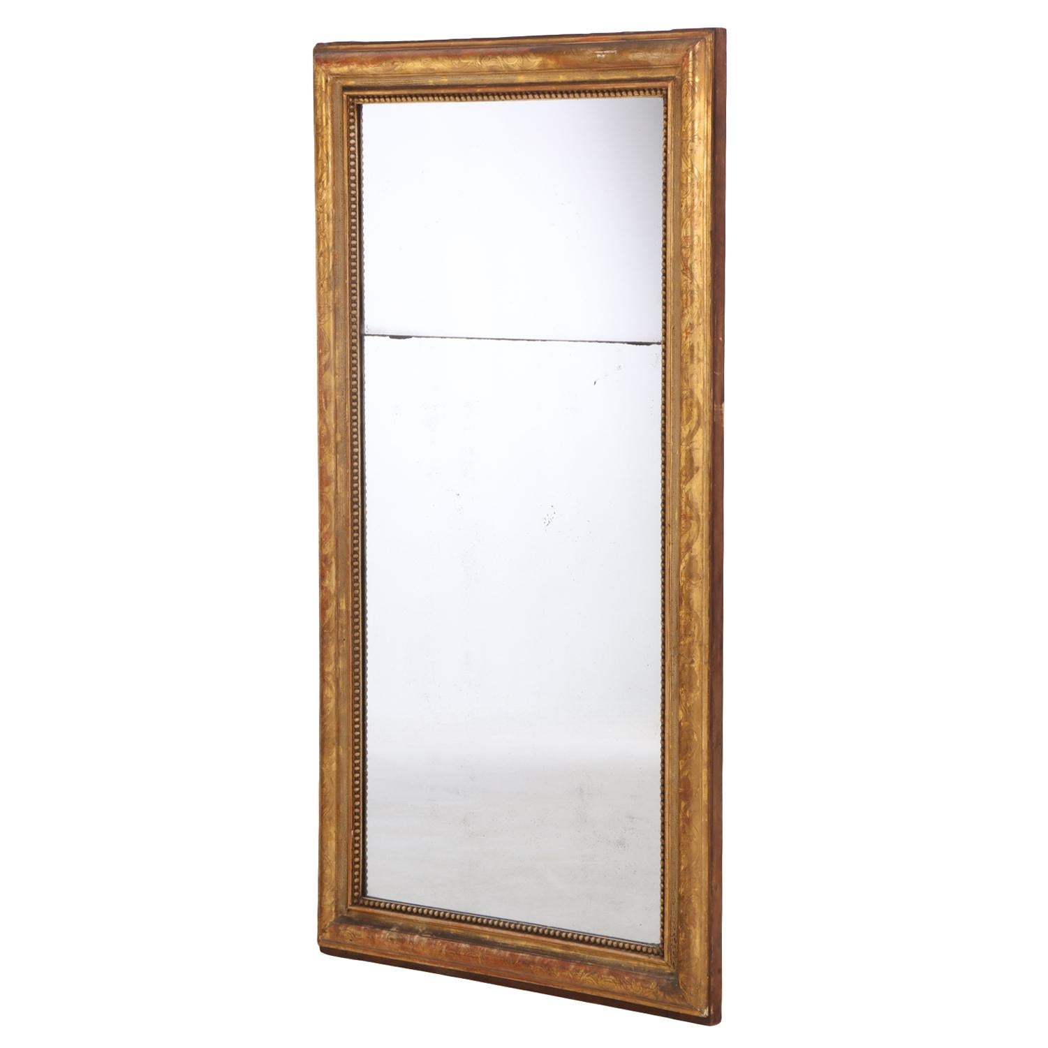 Ce miroir polyvalent est doté d'une plaque de verre d'origine en deux parties, placée dans un cadre moulé et doré, accentué par une bordure intérieure perlée. La forme sobre et la finition chaude à la feuille d'or incarnent la simplicité raffinée de
