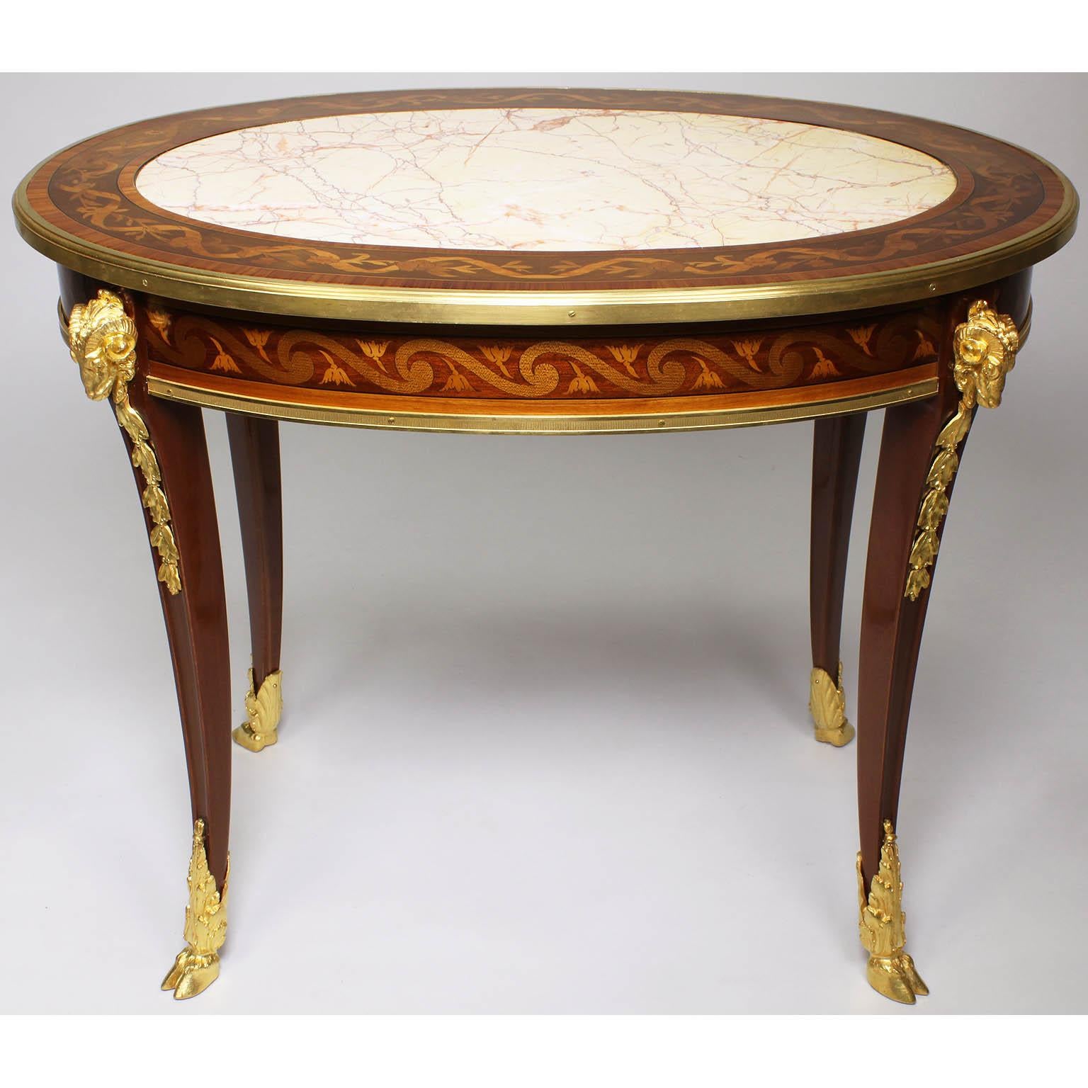 A very fine French Louis XV style Belle Époque figural ormolu-mounted mahogany, tulipwood and fruitwood marquetry oval coffee table with marble top, in the manner of François Linke (1855-1946). The low table with a finely inlaid border top and apron