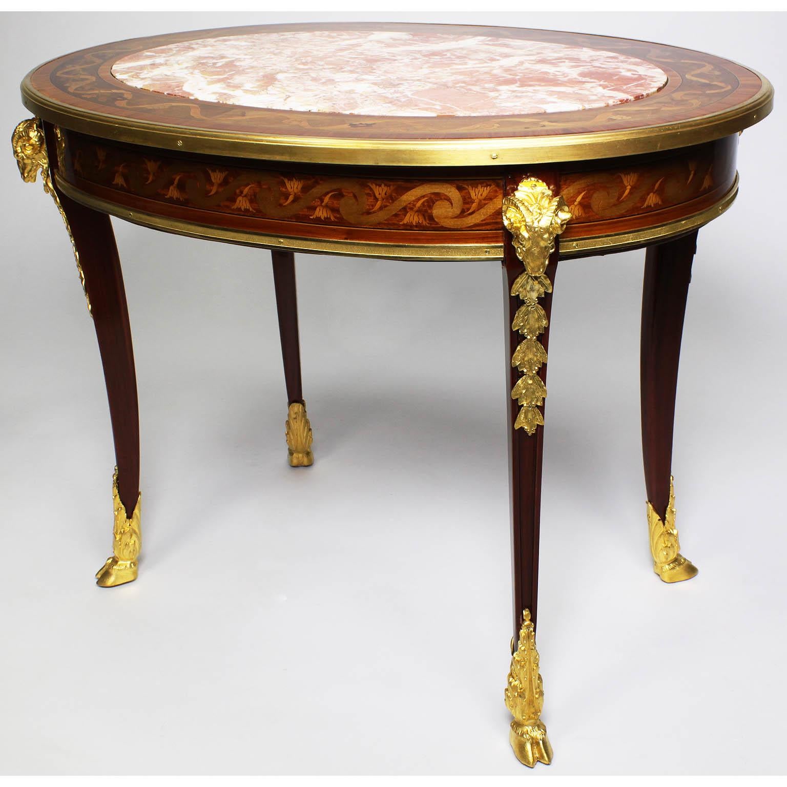 A very fine French Louis XV style Belle Époque Figural ormolu-mounted mahogany, tulipwood and fruitwood marquetry oval coffee table with marble top, in the manner of François Linke (1855-1946). The low table with a finely inlaid border top and apron