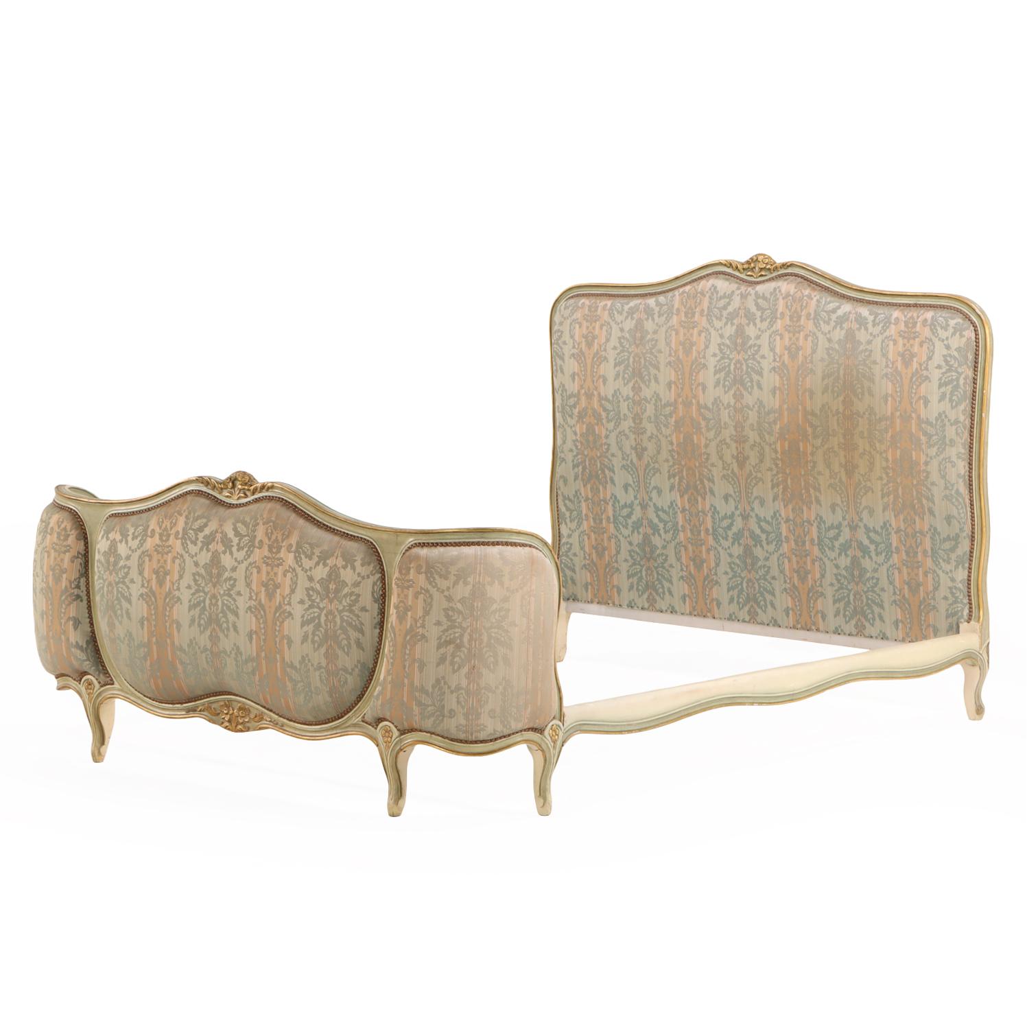 Elegante e romantico nelle forme, questo letto presenta una testata imbottita e una pediera curva all'interno di una cornice intagliata e dorata. La silhouette a corbeille (cesto) e i contorni ispirati alla cabriole riflettono le graziose